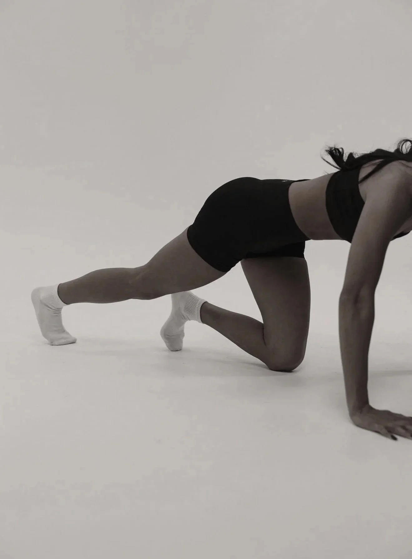 Black-and-white movement photograph from the Sculptd website of a person performing a mat exercise