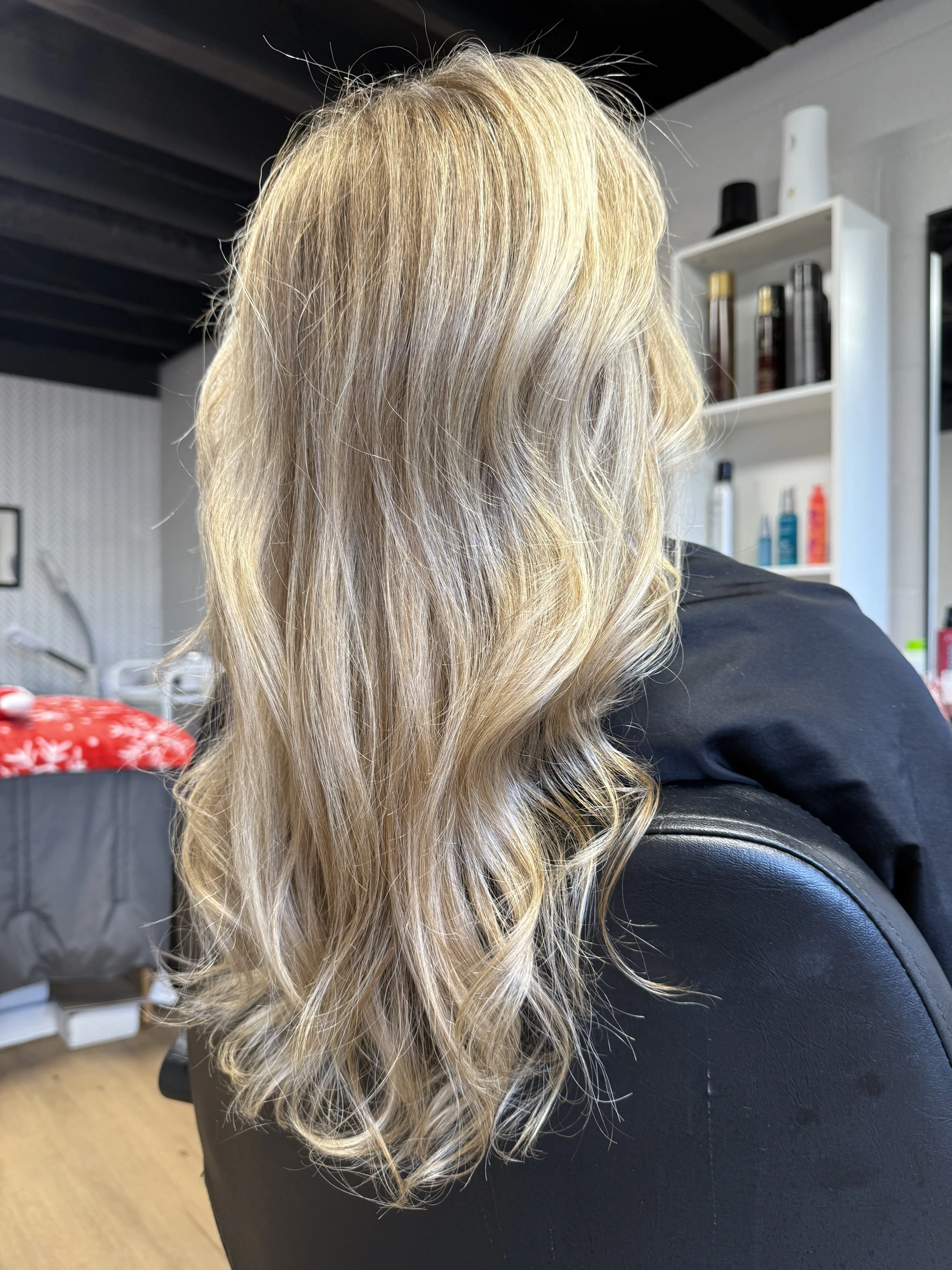 Blonde hair with loose curls sitting on a black salon chair in a hair salon.