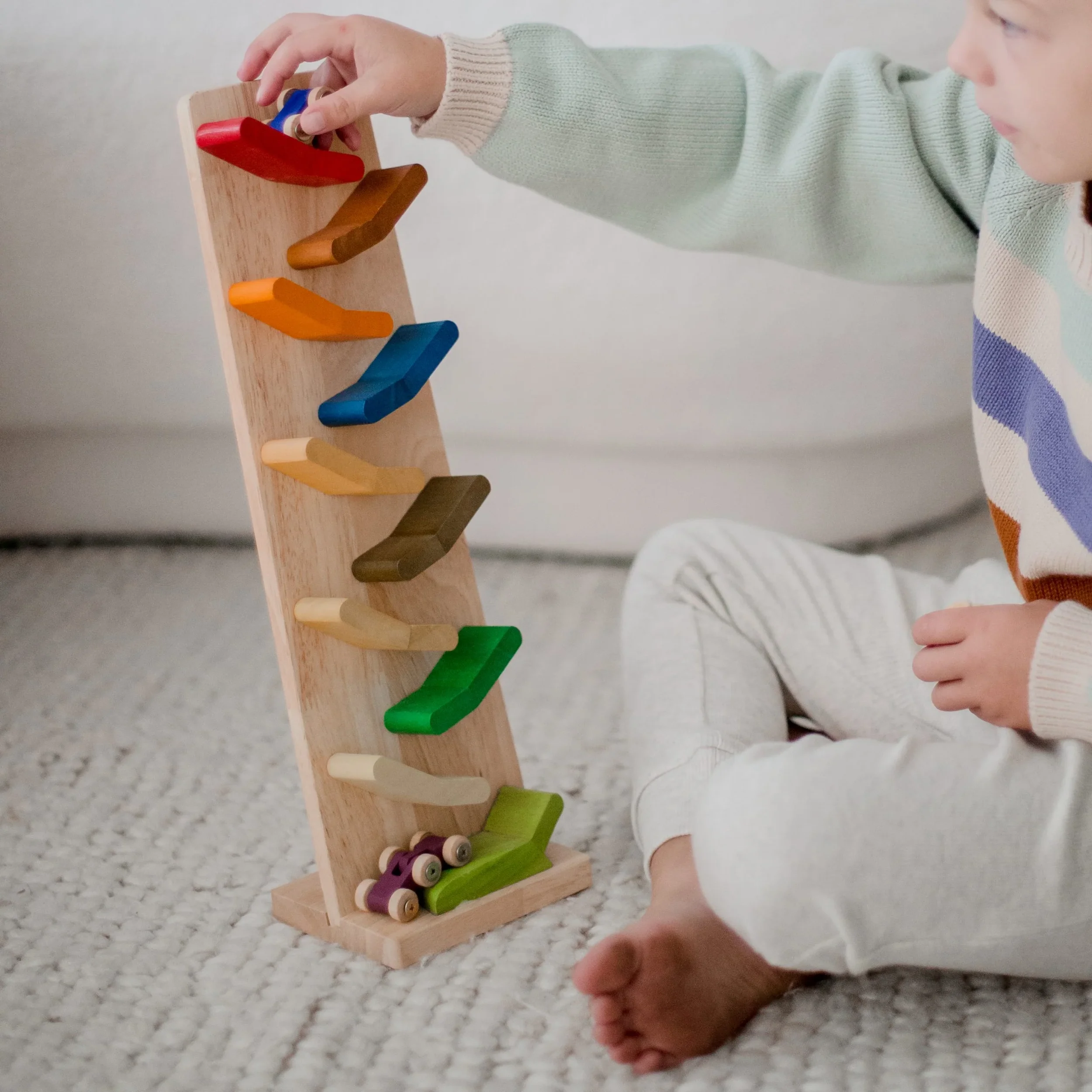 A child playing with a wooden peg puzzle featuring colorful wooden pegs of various shapes and colors.