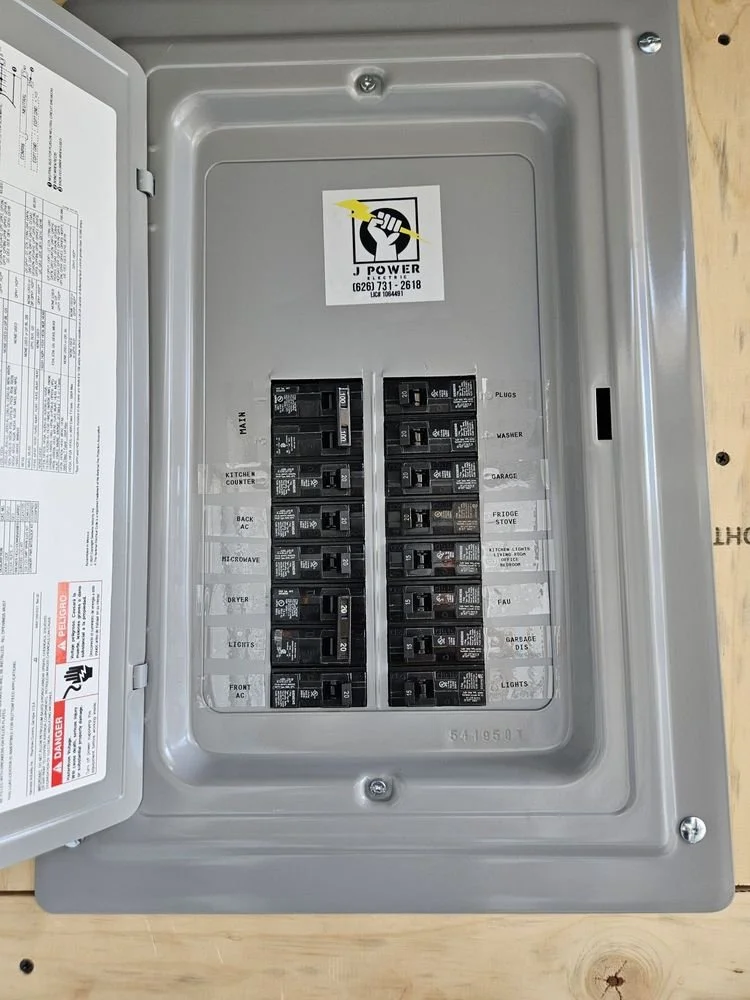 Electrical fuse box with labeled circuit breakers for various household appliances and areas, including main, kitchen counter, back AC, microwave, dryer, lights, front AC, plugs, washer, garage, fridge, stove, kitchen lights, laundry, garage disc, and lights.