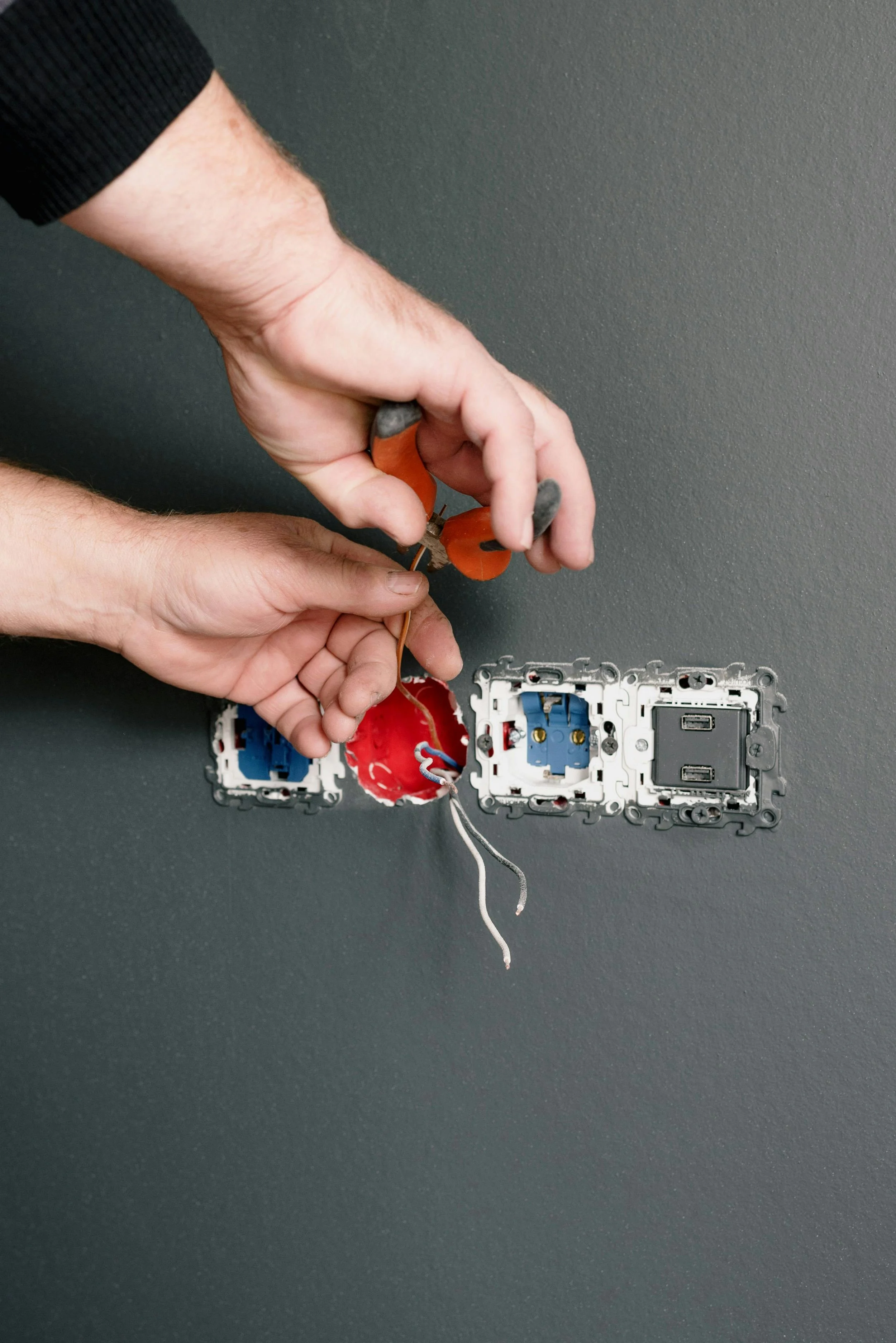 Person installing electrical outlets and switches into a wall.