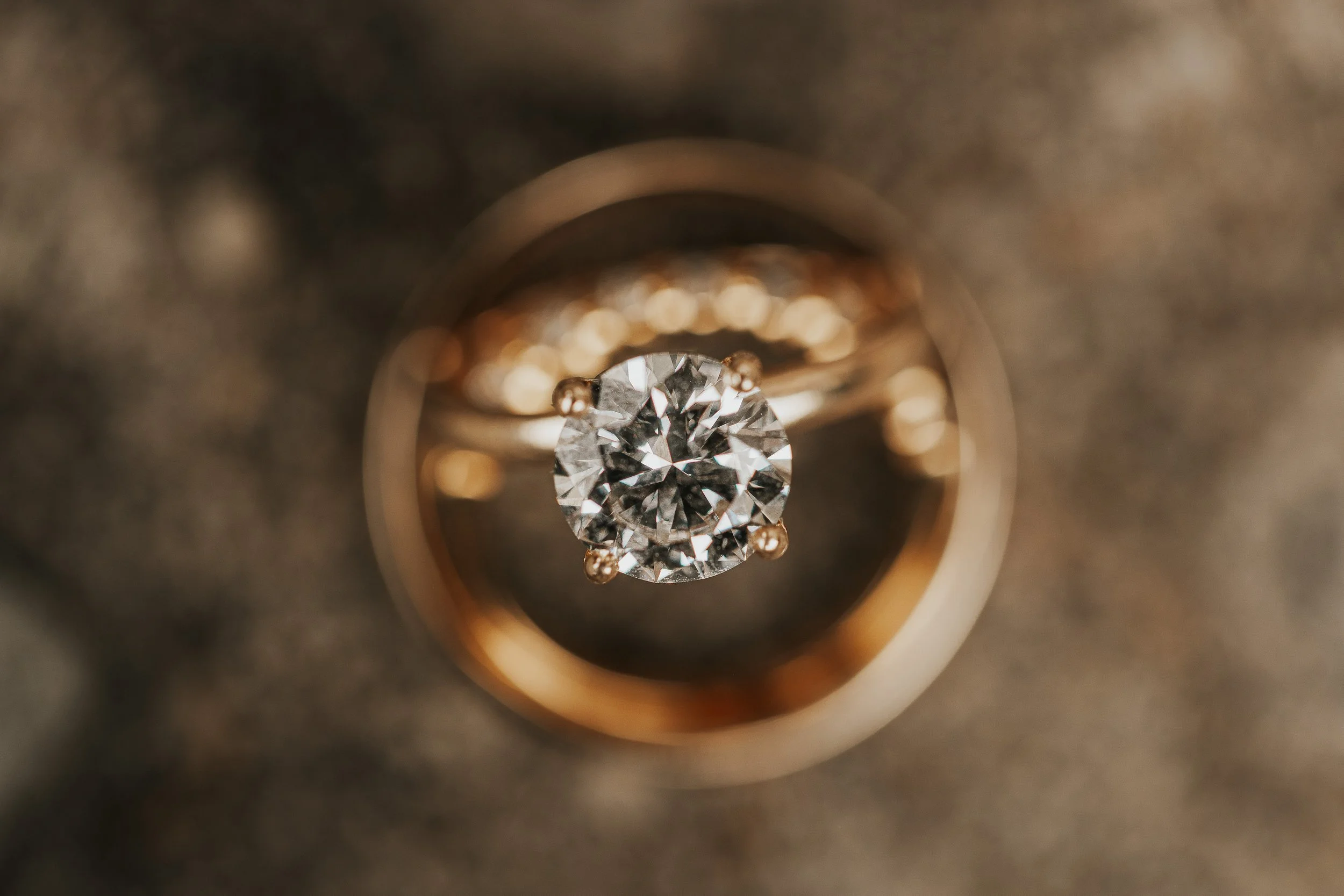 Close-up of a diamond ring with a large round diamond in a setting, viewed through a circular opening.