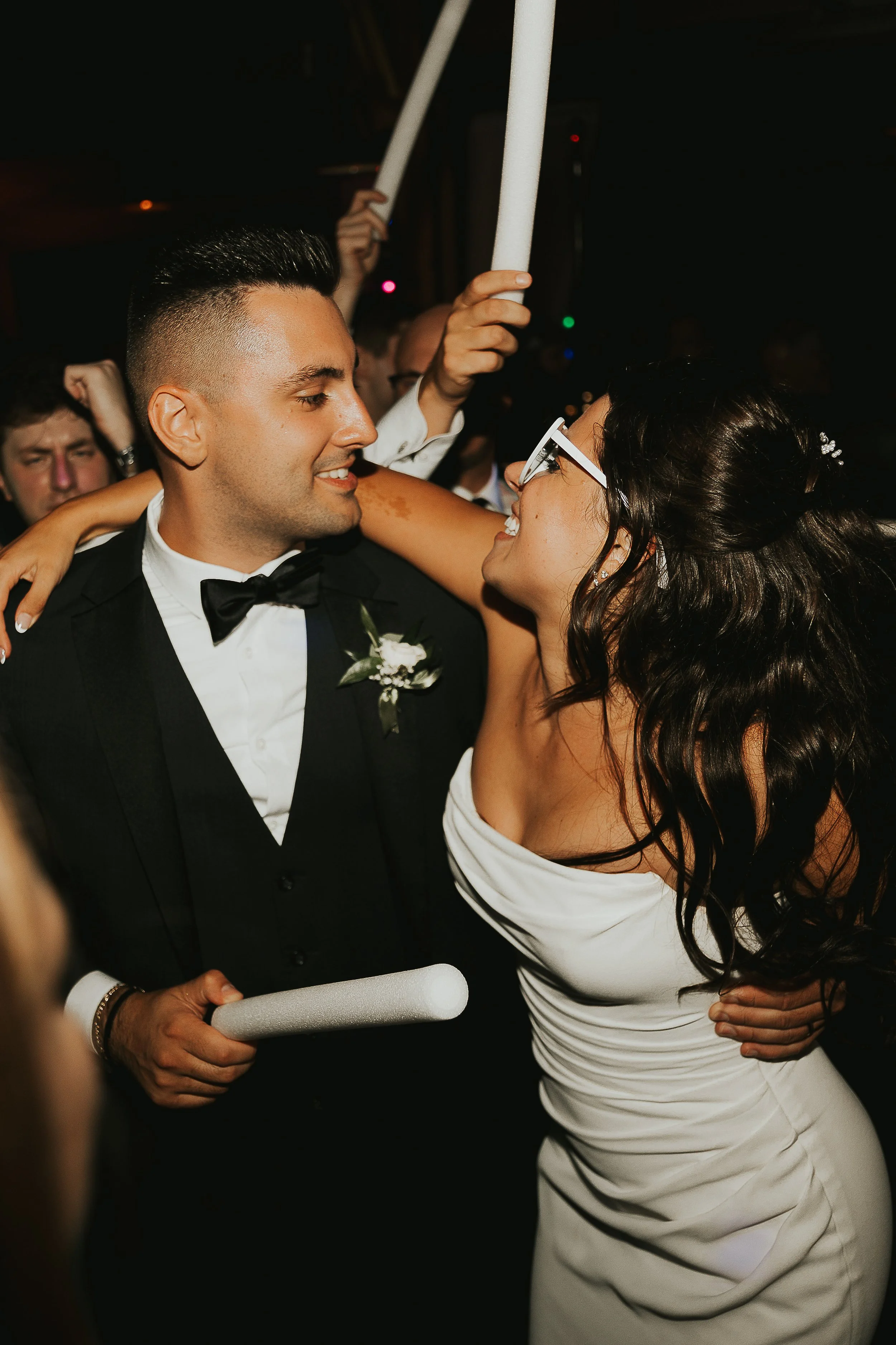 A groom and bride dancing closely at their wedding reception, surrounded by guests.