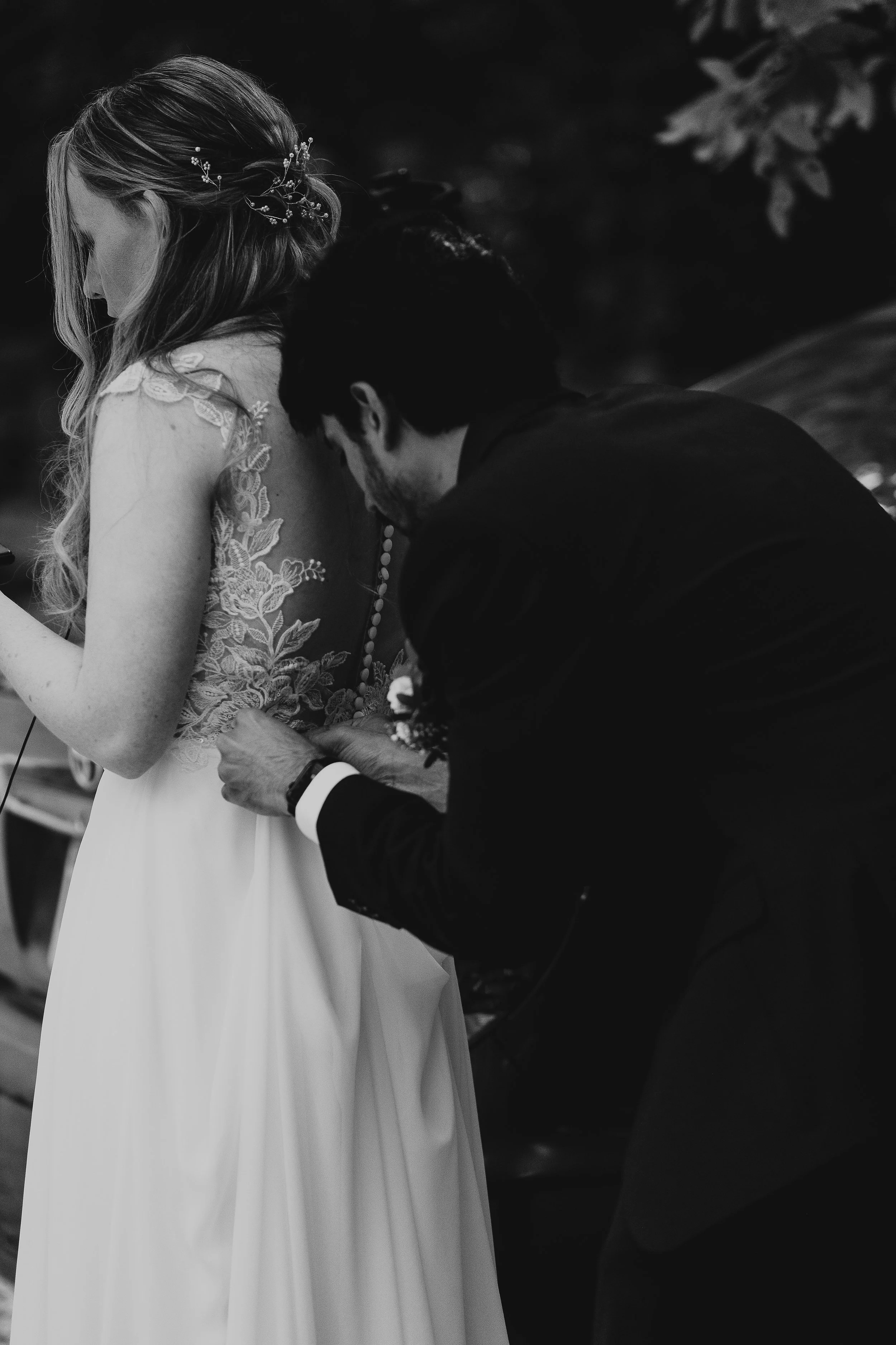 A man in a suit adjusting a woman in a wedding dress during a wedding ceremony.