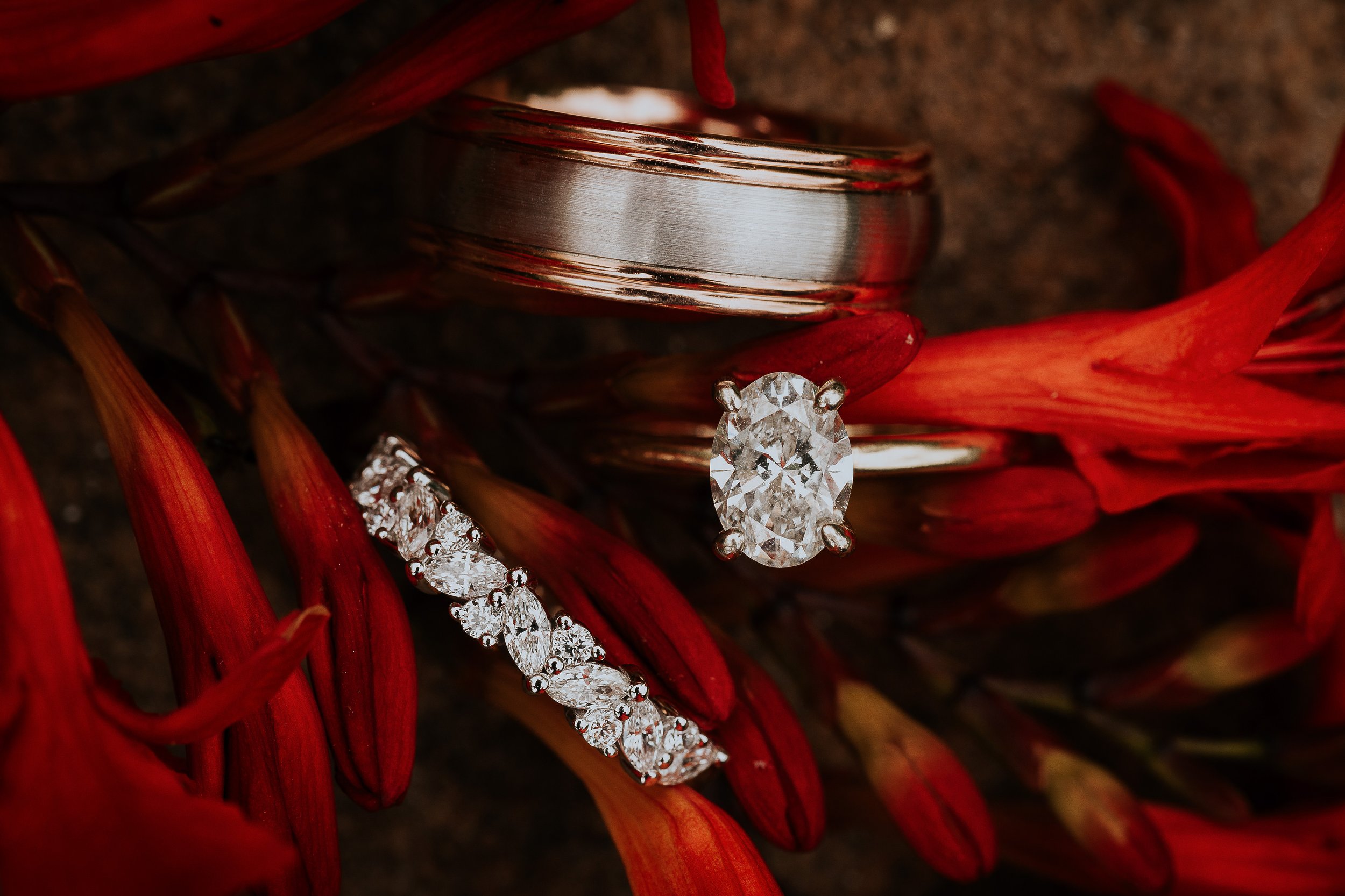 Close-up of a silver ring with a brushed finish, decorated with clear gemstones, placed on red and orange woven material.