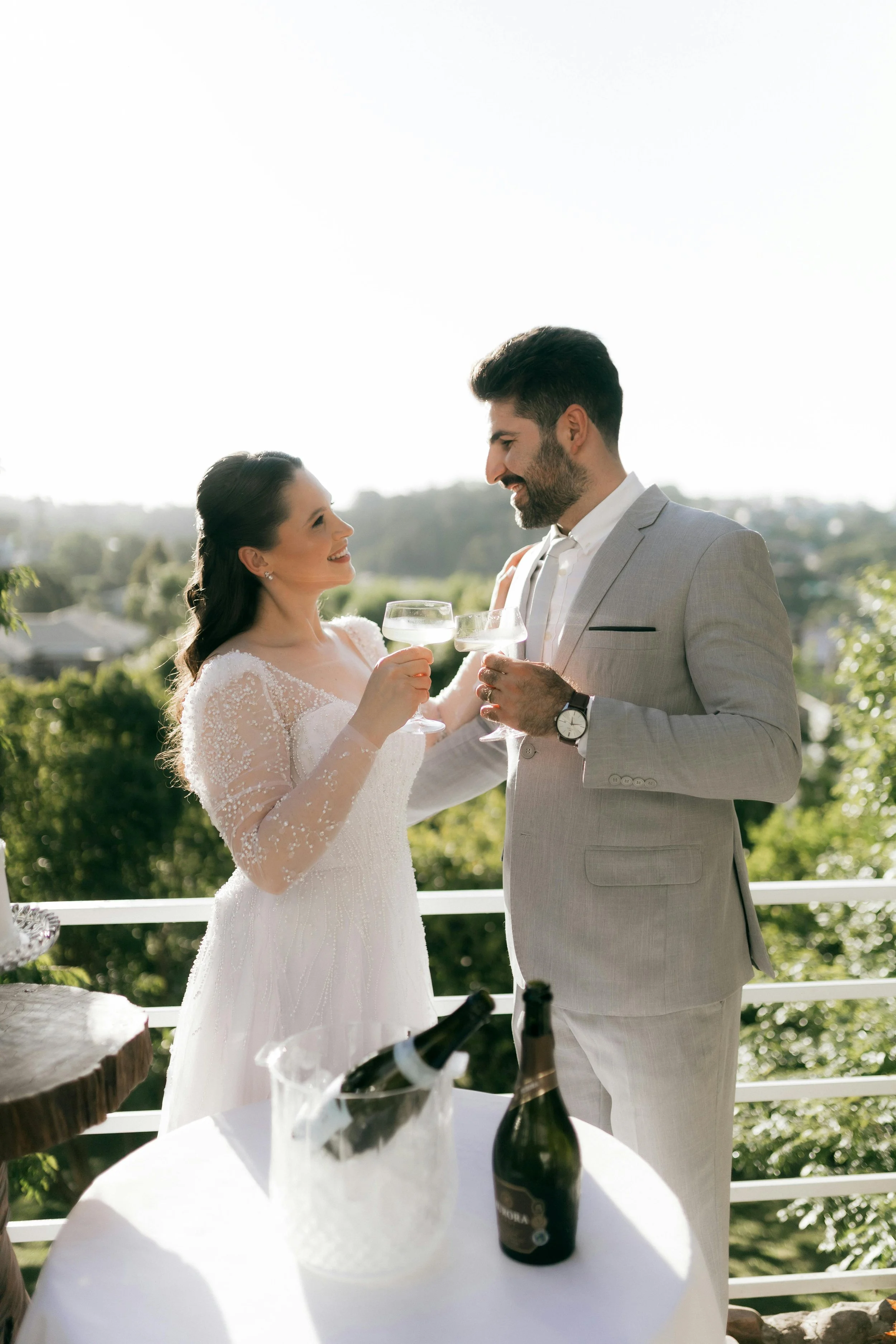 Bride and groom celebrating with champagne on outdoor balcony with scenic view