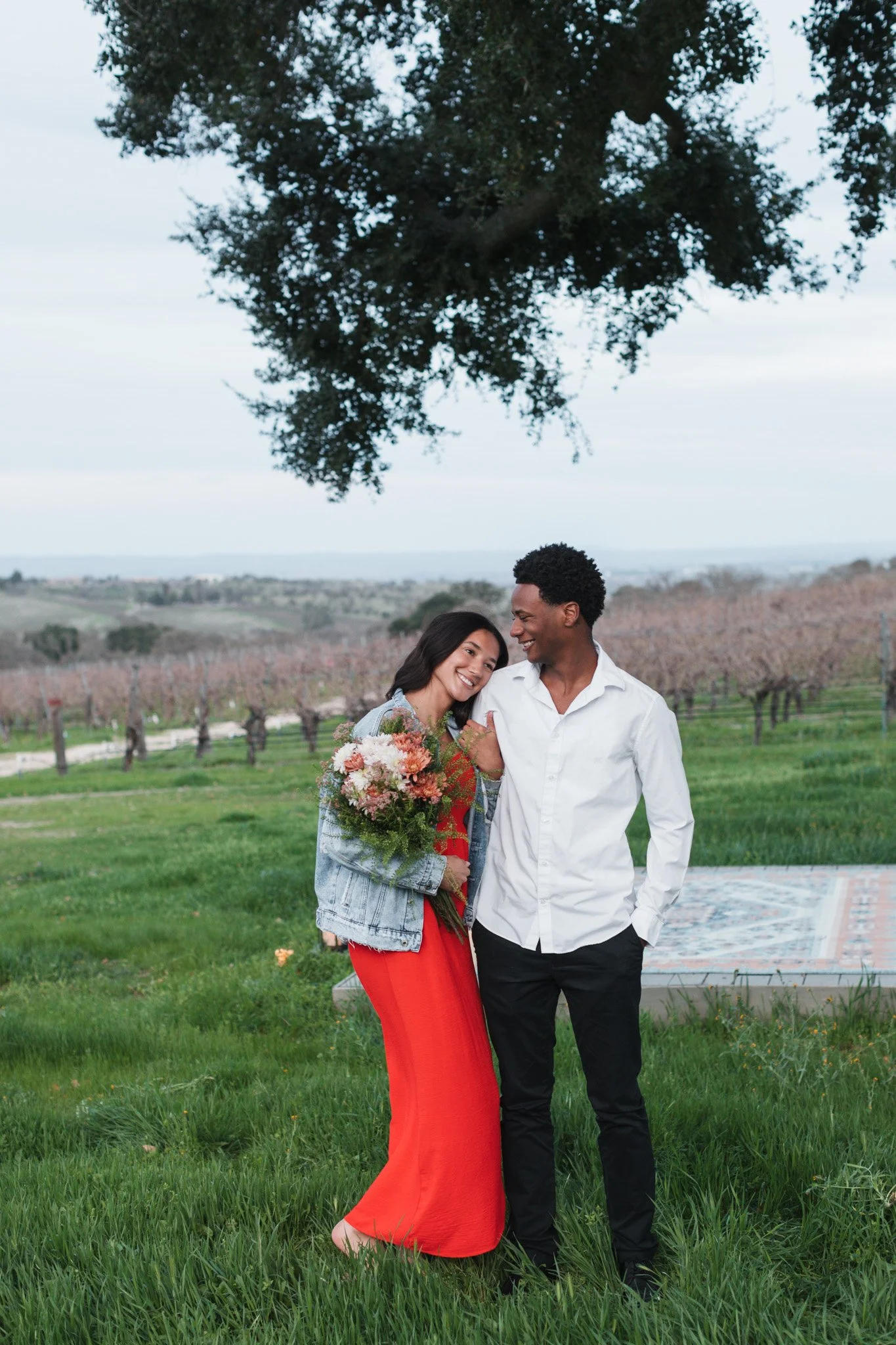 Couple smiling together in a Central Coast meadow with a bouquet during an intimate elopement portrait session.