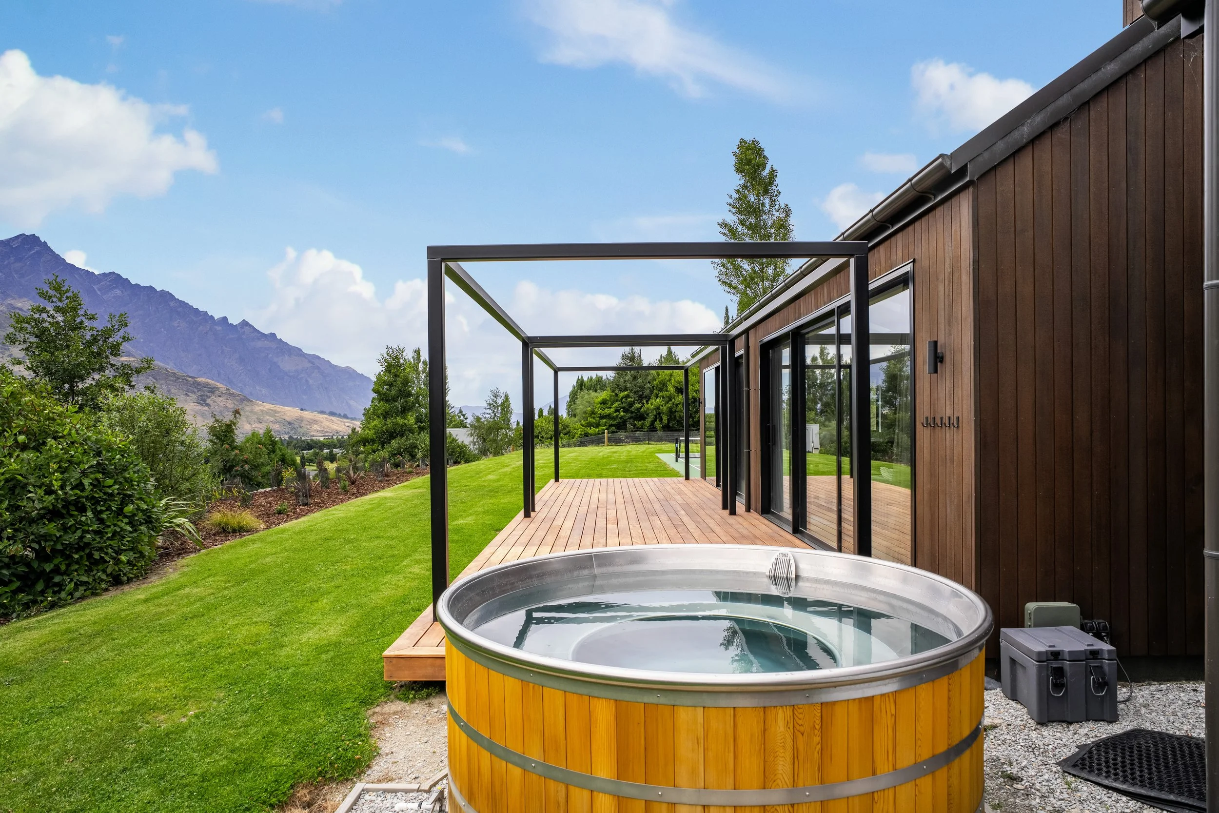 The view looking across an outdoor hot tub over outdoor decking of Quailstone, a Queenstown holiday home managed by Be Our Guest