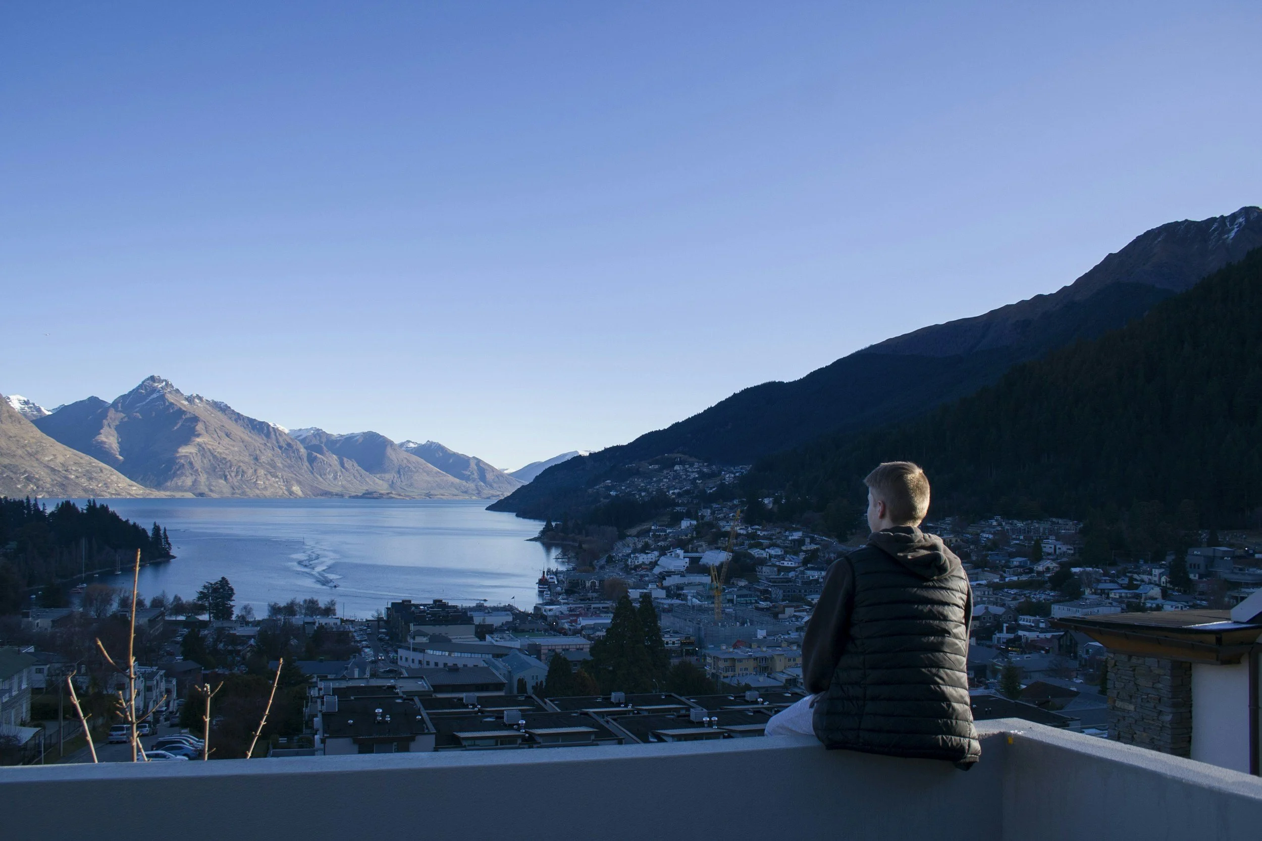 An individual sitting on a balcony looking over Queenstown.