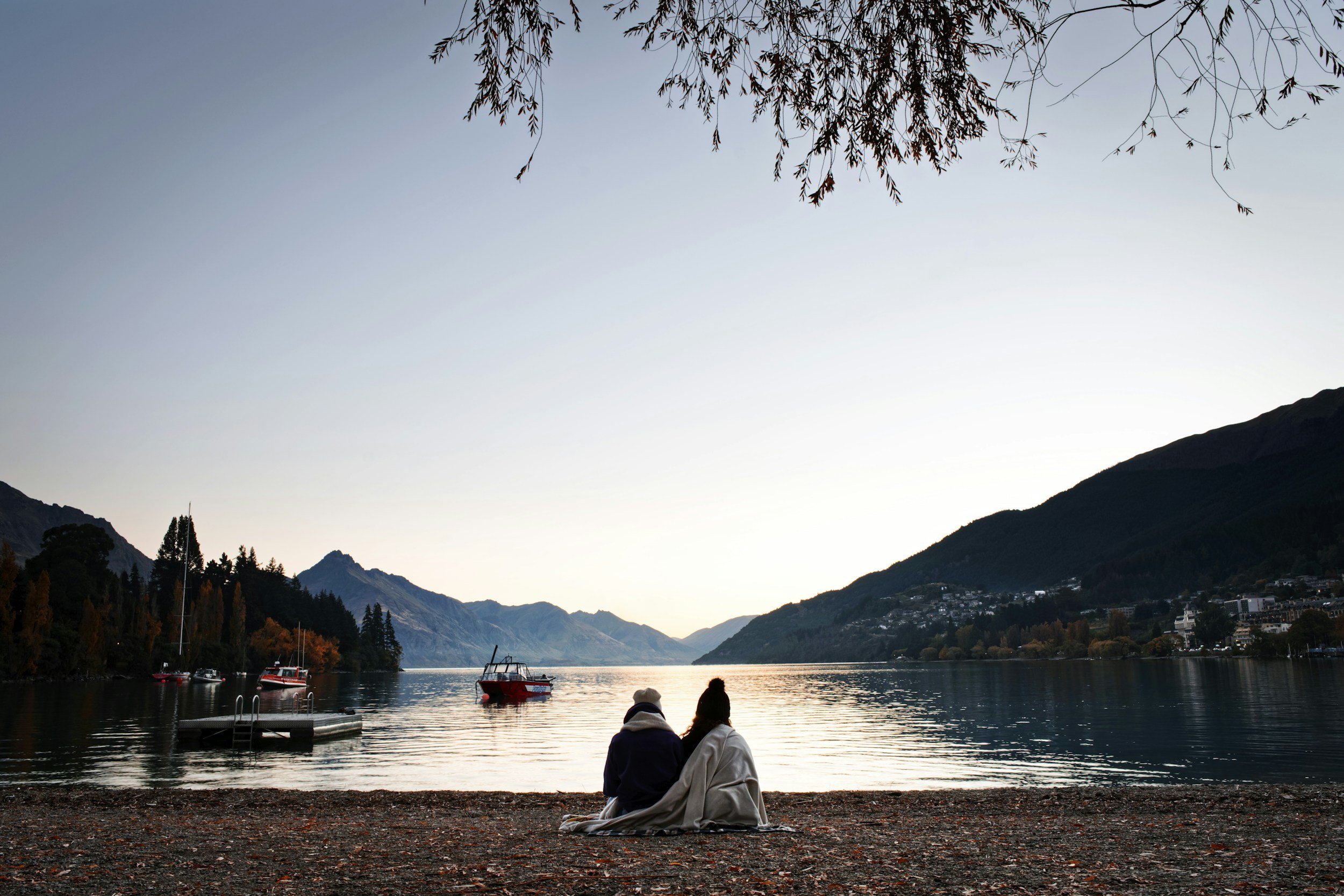 A couple sitting together at the lakes edge in Queenstown.