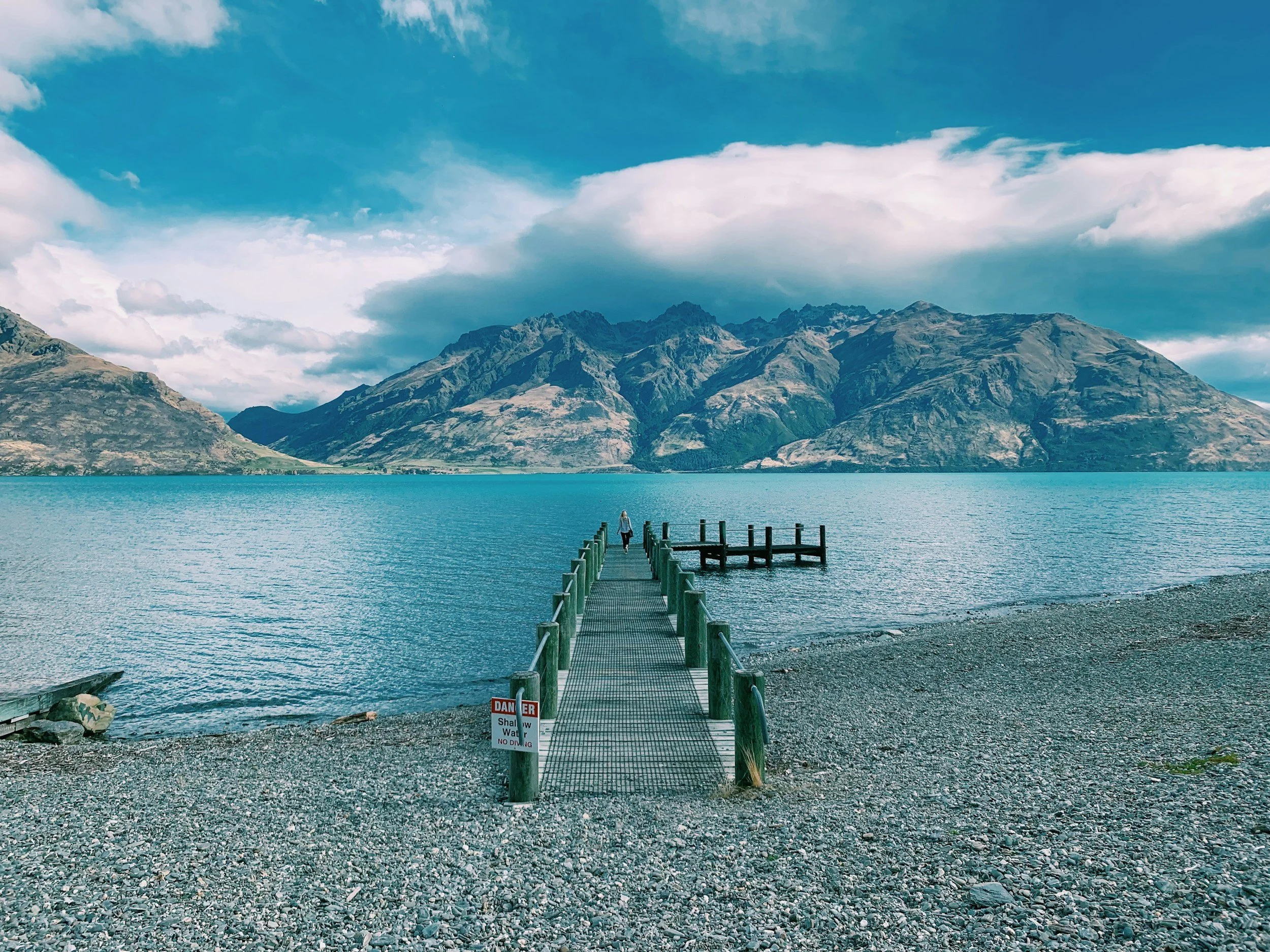 Looking out from a beach on Lake Wakatipu over a wharf.