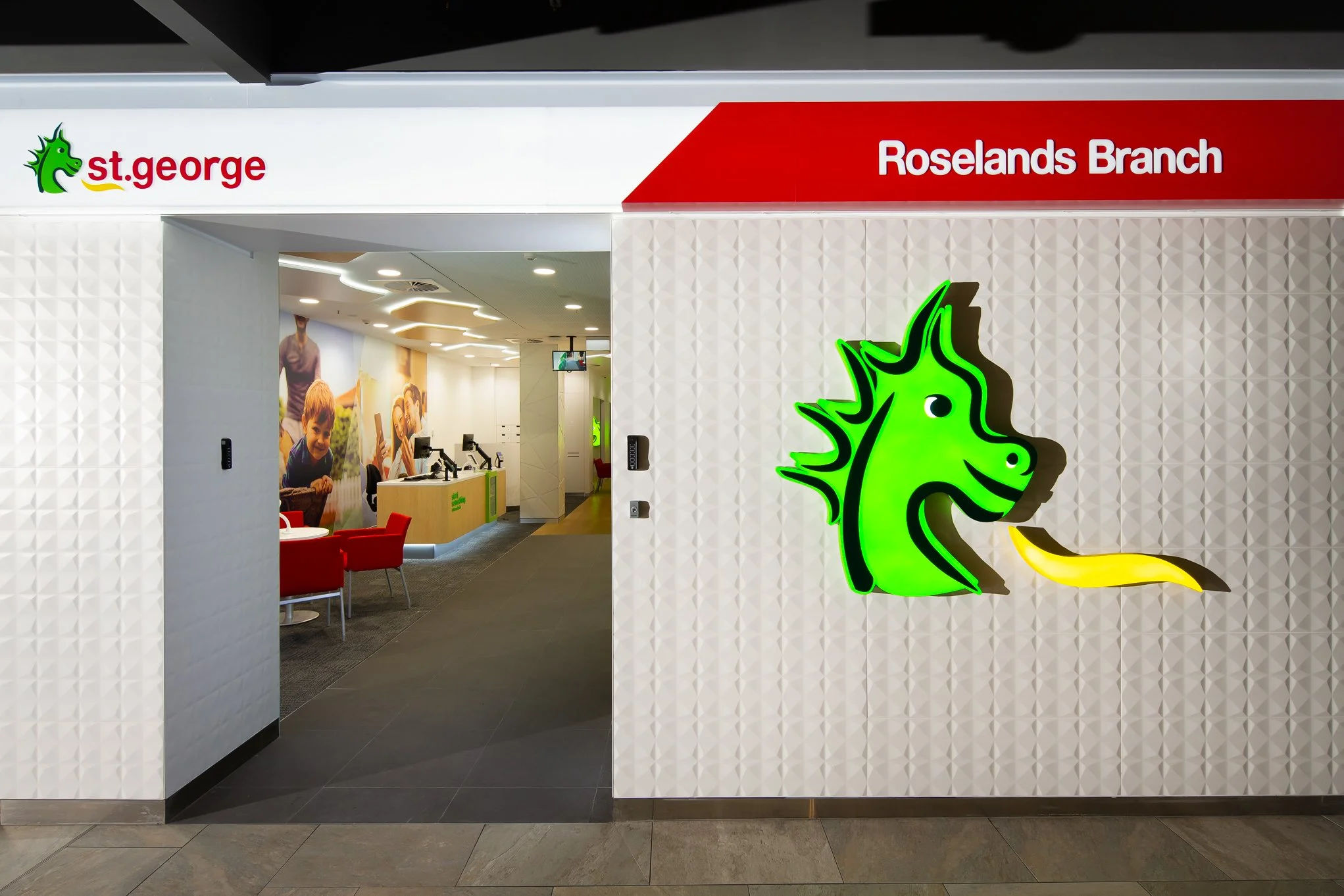 Entrance to a St. George store's Roselands Branch with a green neon seahorse logo on a white patterned wall.