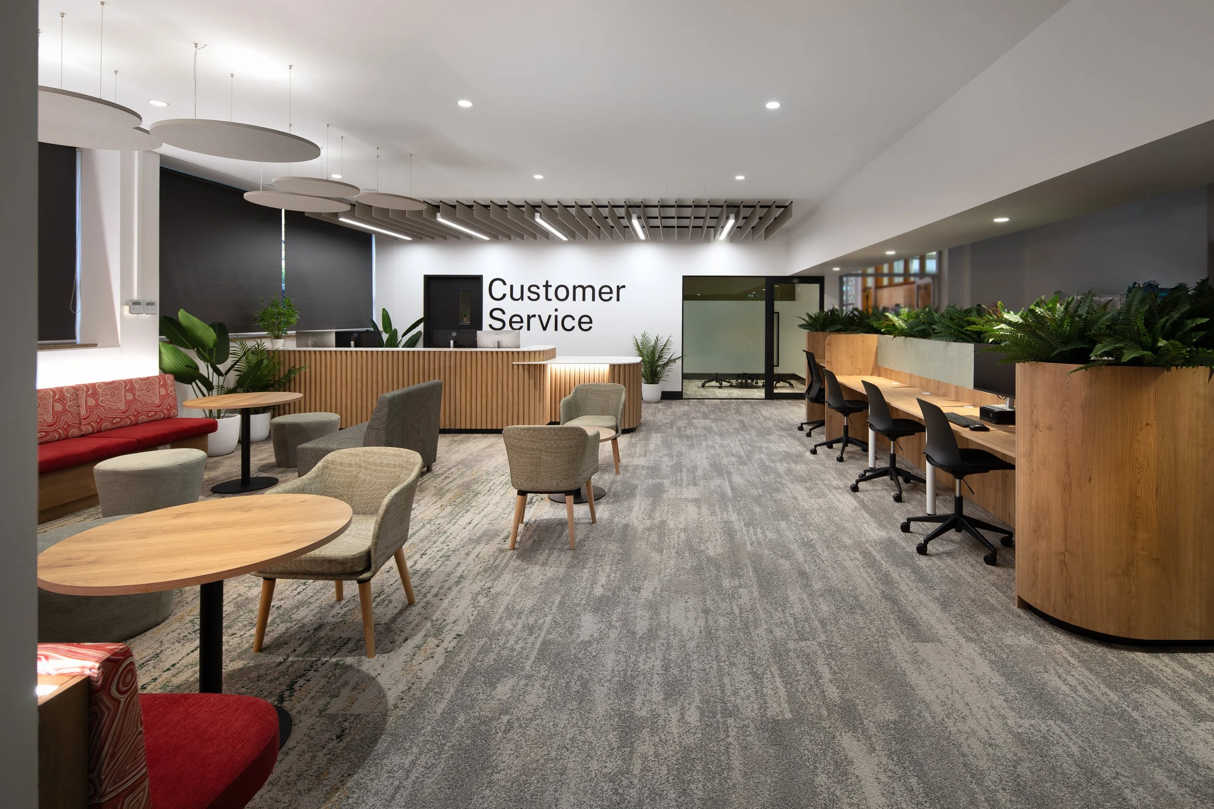 Interior view of a customer service area with seating, plants, and workstations.