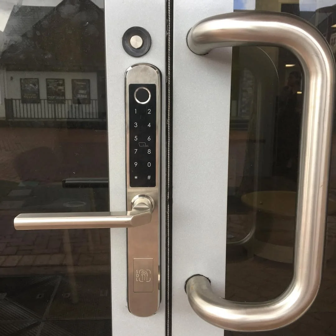 Glass door with a keypad lock, door handles, and an access card scanner.