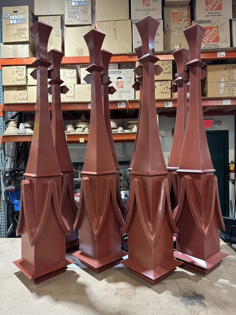 Four tall, decorative aluminum finials with a geometric, art deco style. They are made of aluminum metal and painted a dark red color, with a tiered design at the top resembling stylized flames or crowns.