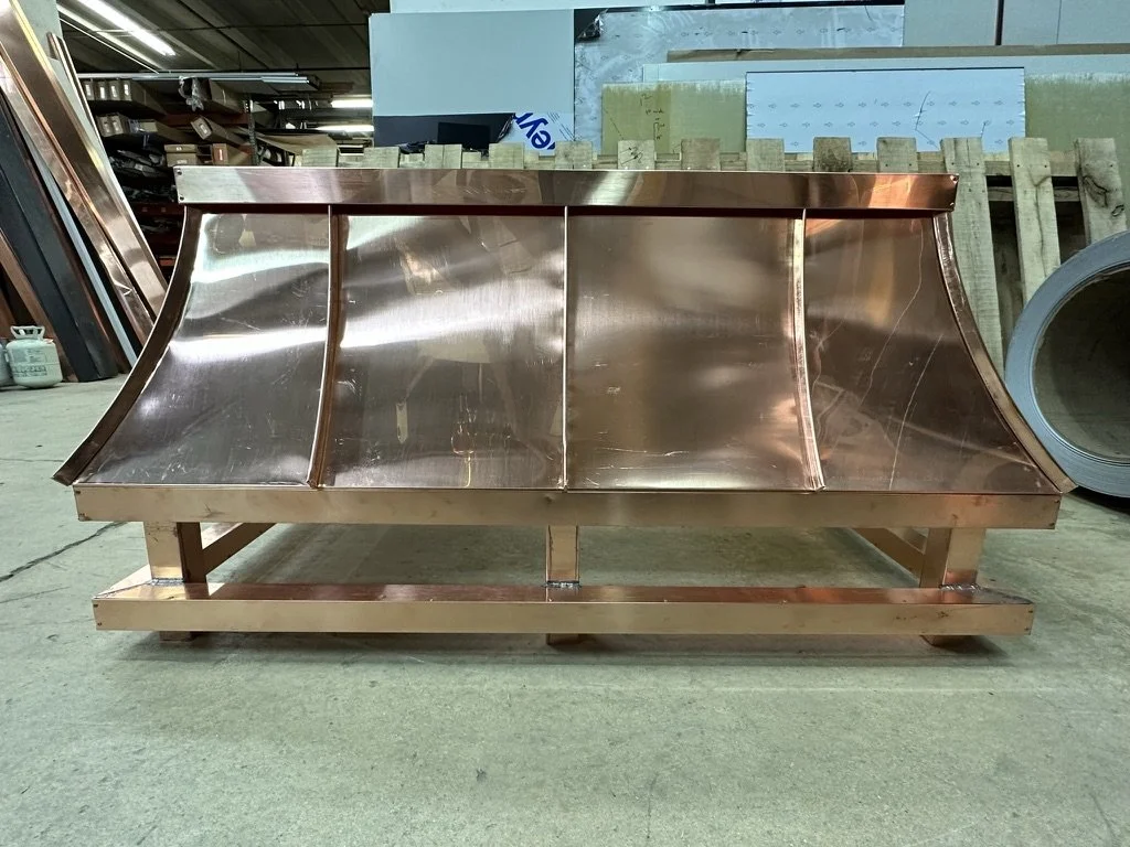 A large copper chimney shroud with curved sides and a solid copper frame.