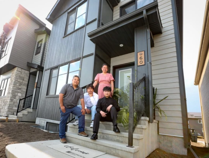 A family of four standing on the front porch of their modern house.