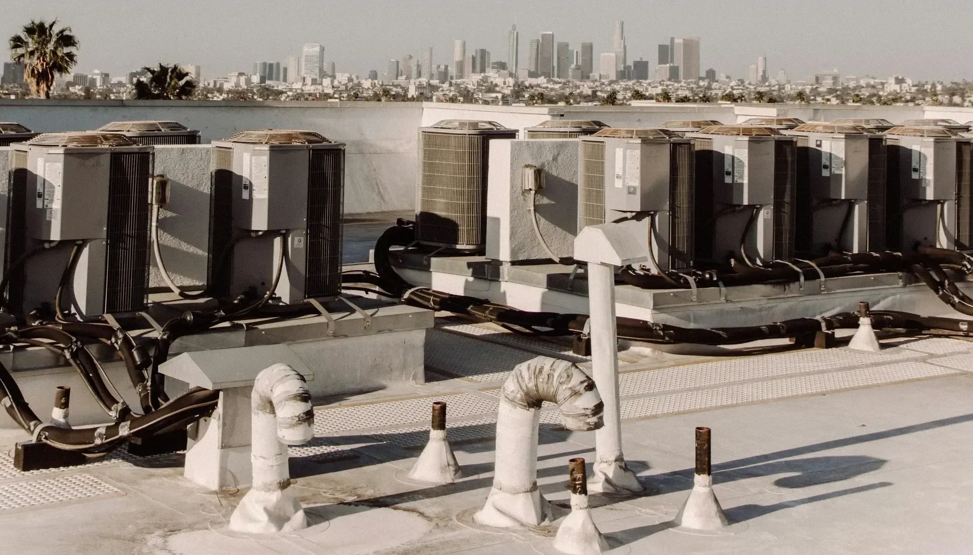 Rooftop air conditioning units with city skyline in the background.