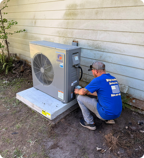 A technician working on an outdoor air conditioning unit next to a house wall.