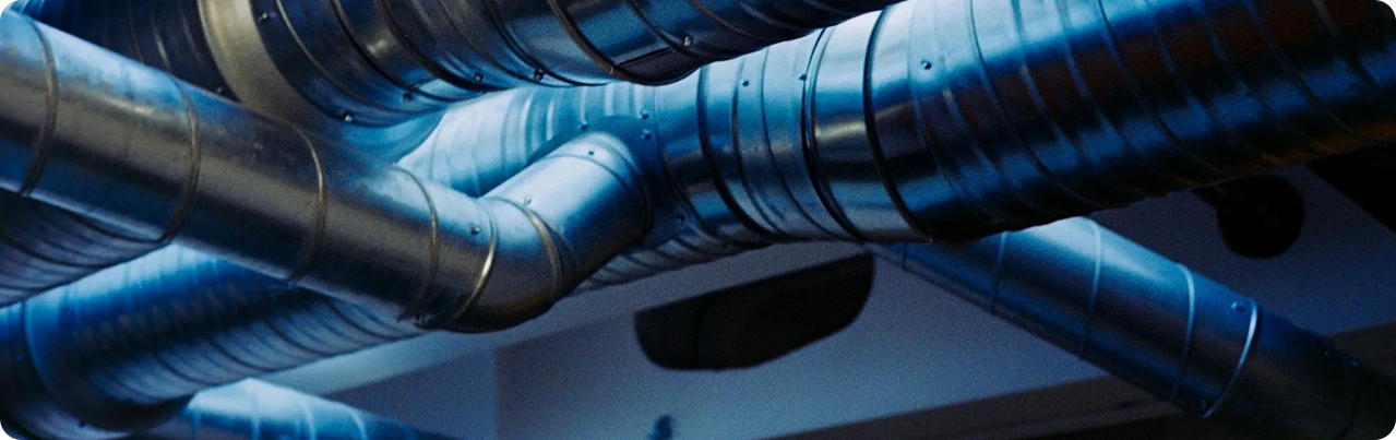 Silver and black industrial ventilation ducts in a building ceiling.
