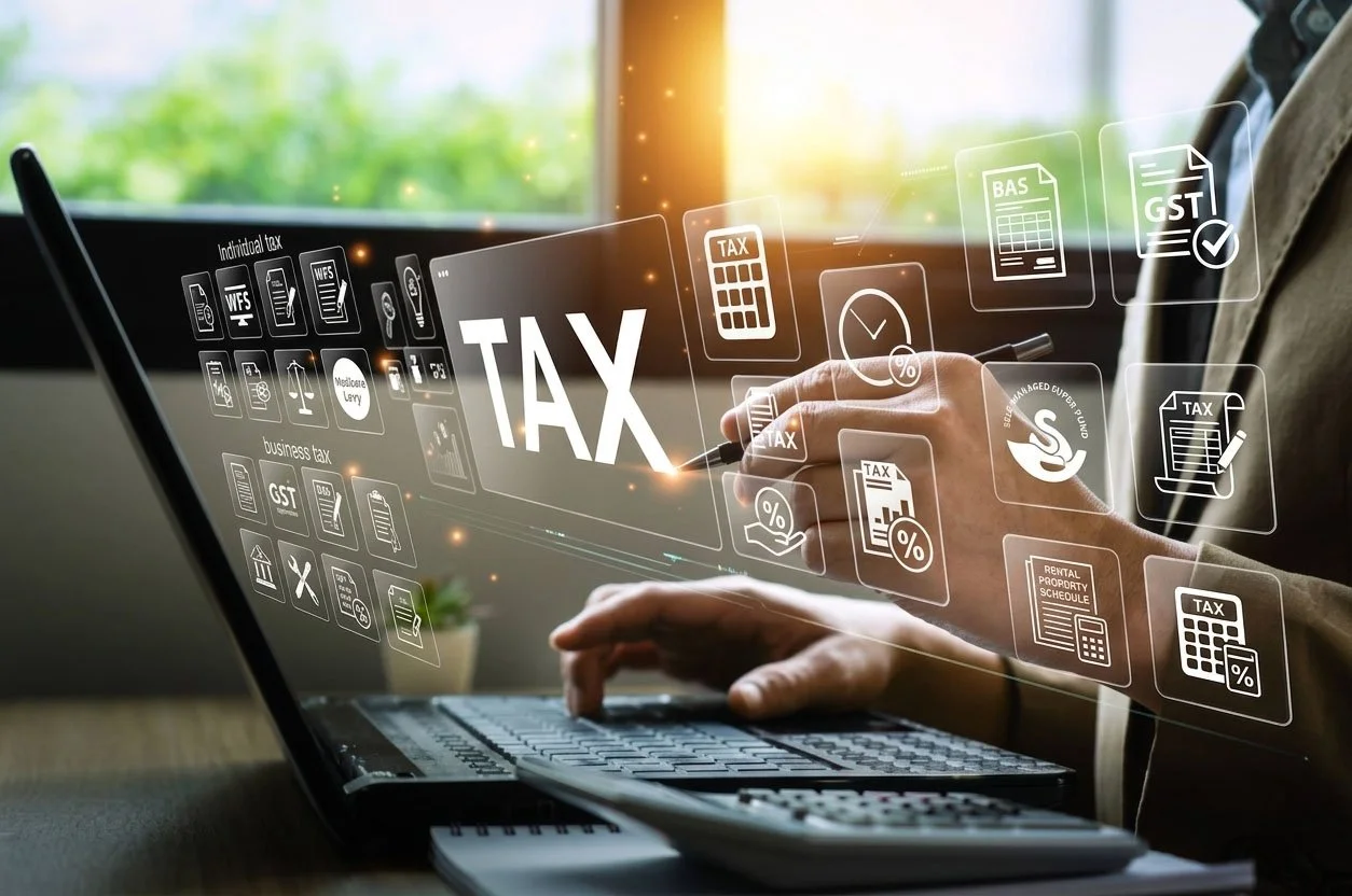 Hands typing on a laptop keyboard with digital icons and text related to taxes floating above the screen, including 'TAX', 'business tax', 'individual tax', and various tax documents.