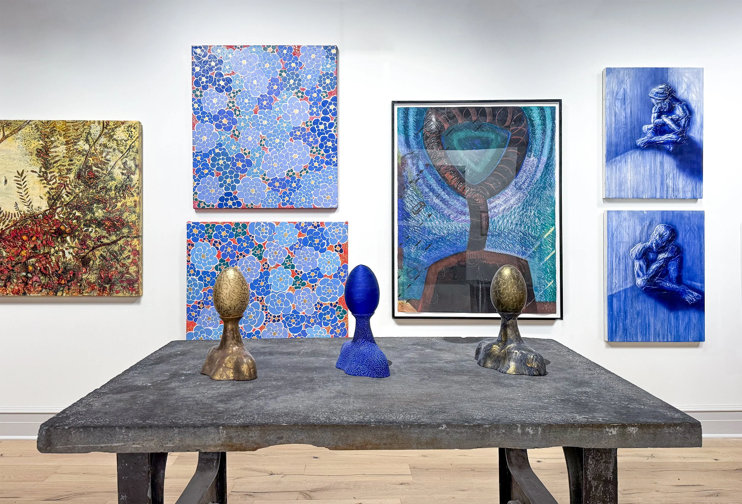 An art gallery with abstract paintings on the wall and decorative vases on a dark wooden table in the foreground.