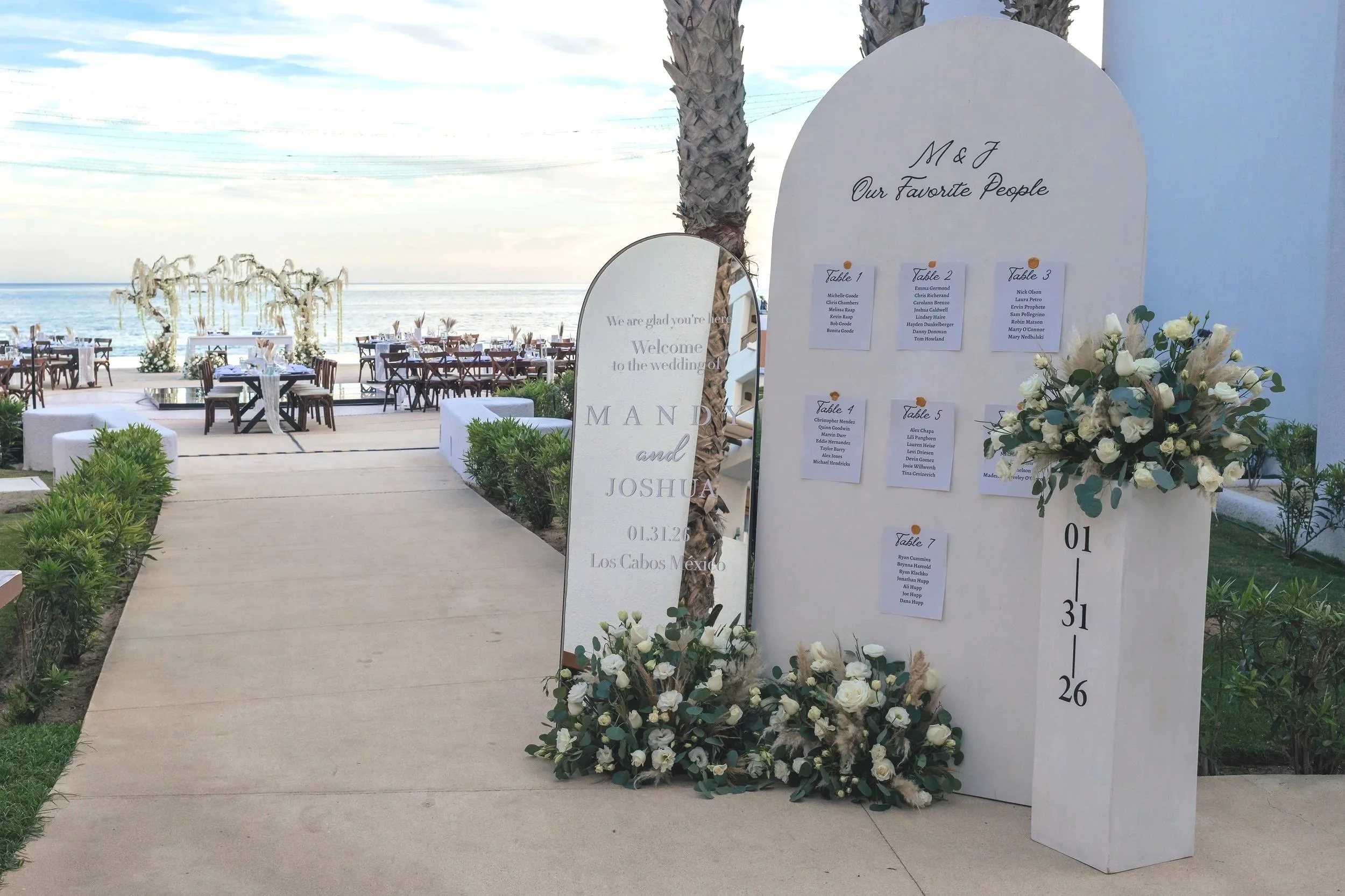 Seaside wedding signage in Los Cabos with seating chart, floral decor, personalized details, and oceanfront event styling by I DO Weddings Los Cabos.