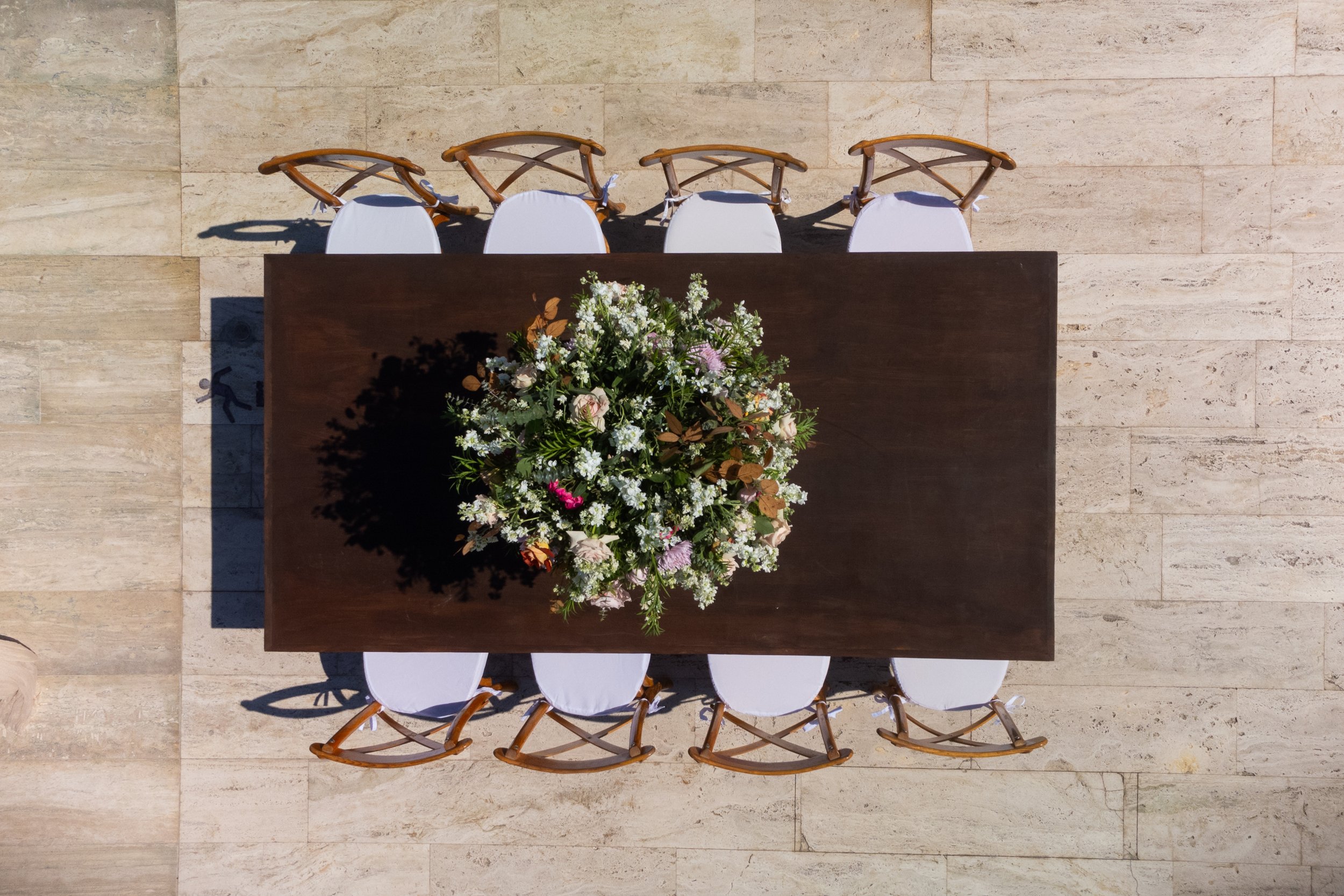 Wedding table setup in Los Cabos with floral arrangement, place settings, chairs, and tabletop decor by I DO Weddings Los Cabos.