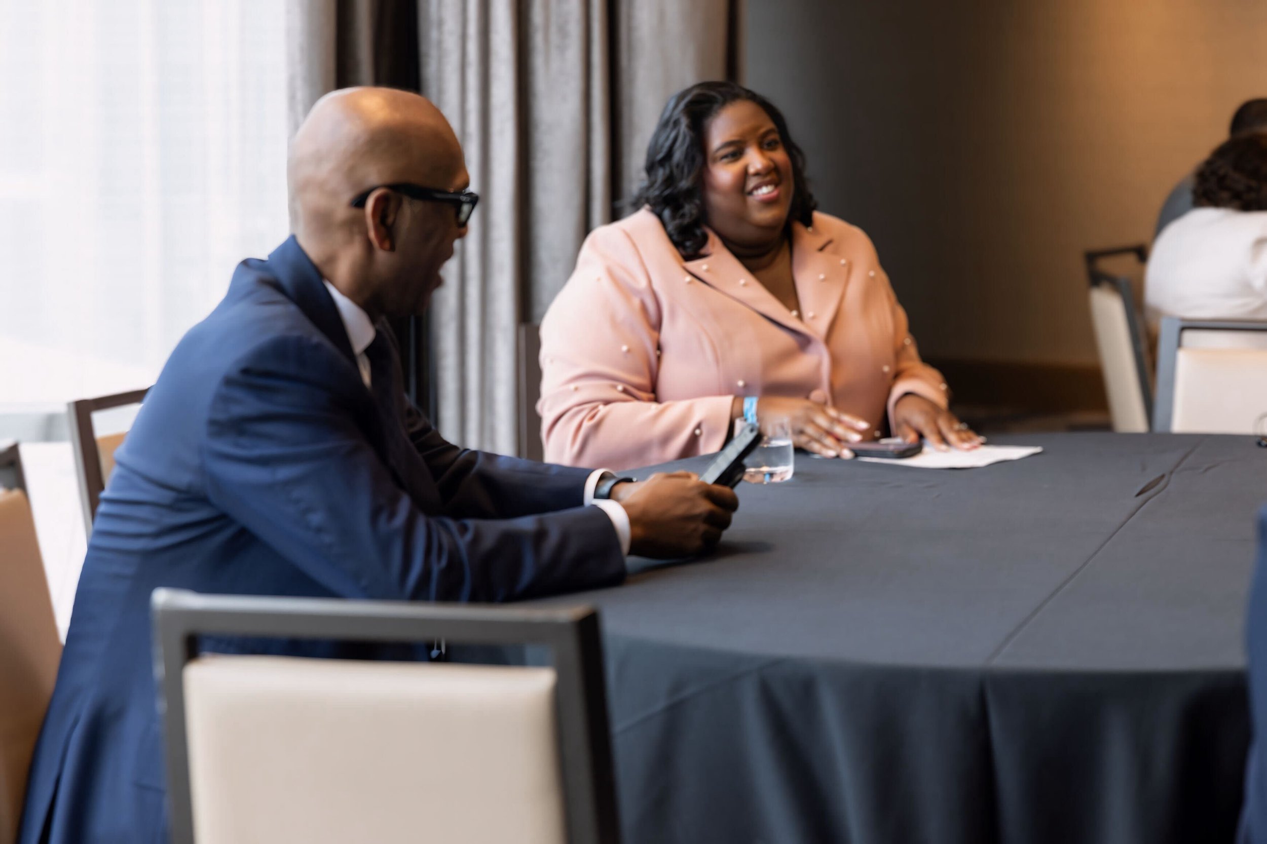 Monchiere' Holmes Jones, Cultural Economist™  with with Bishop Joseph Walker at a conference table, engaged in conversation. 