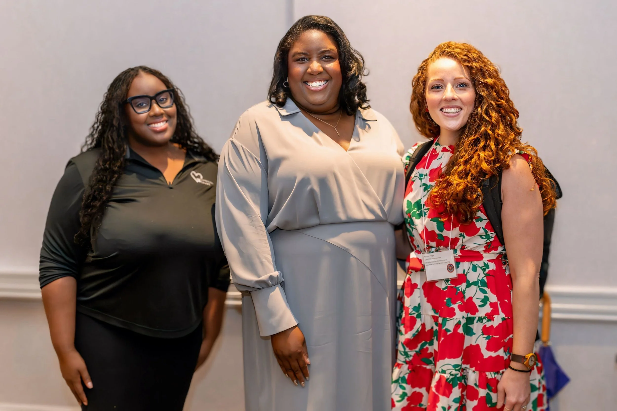 Monchiere' Holmes Jones, Cultural Economist™  with women leaders standing together and smiling at an indoor event.