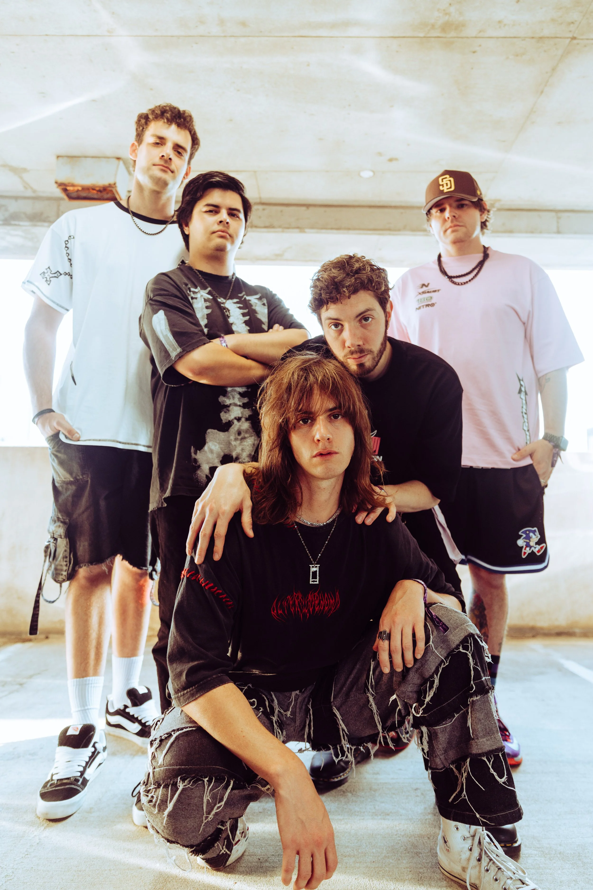 Down and Out, a group of five young men posing in a parking garage, dressed in casual streetwear with distressed clothing and accessories.