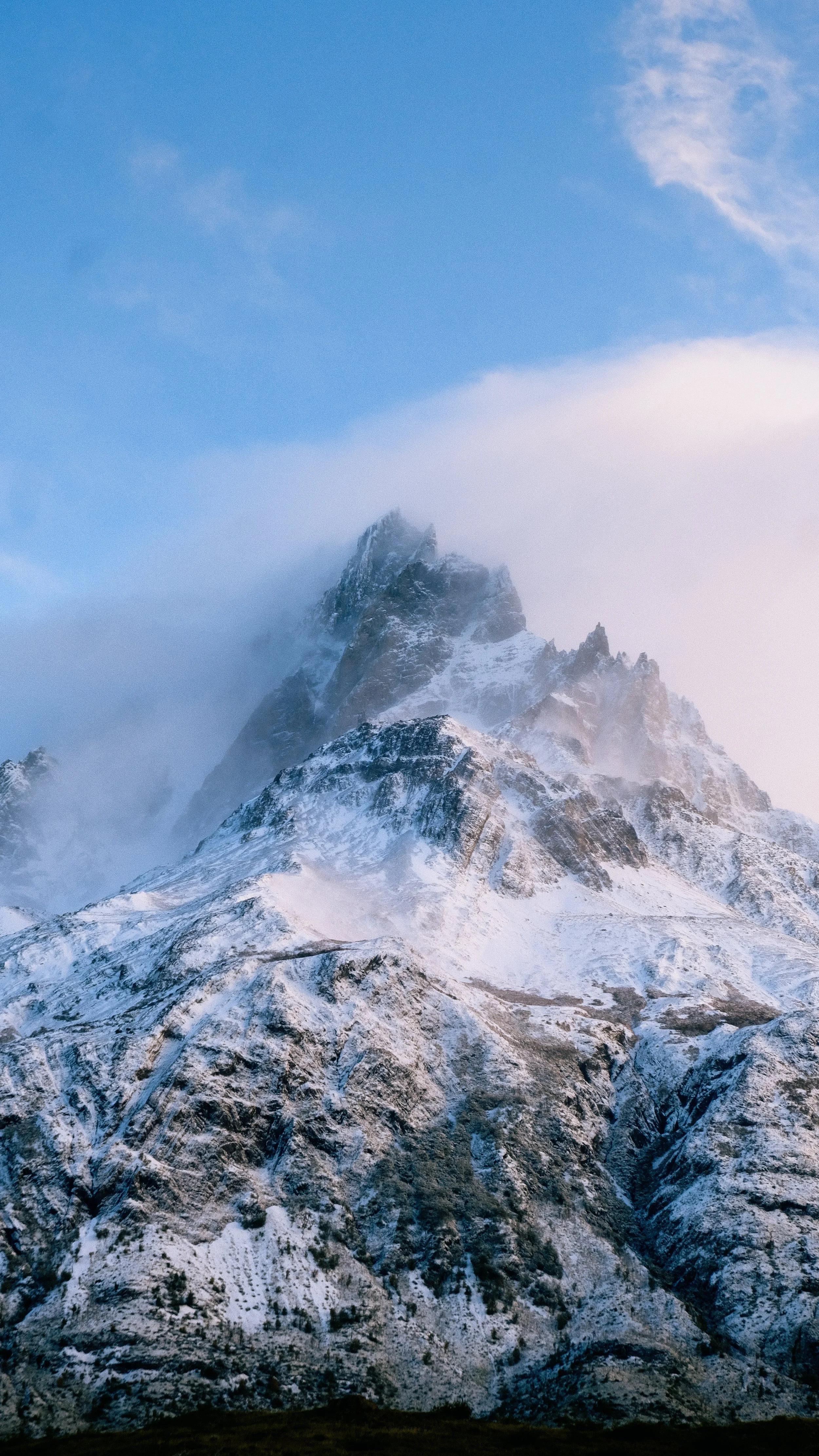 Sneeuw bedekte berg met mist en wolken in de lucht.