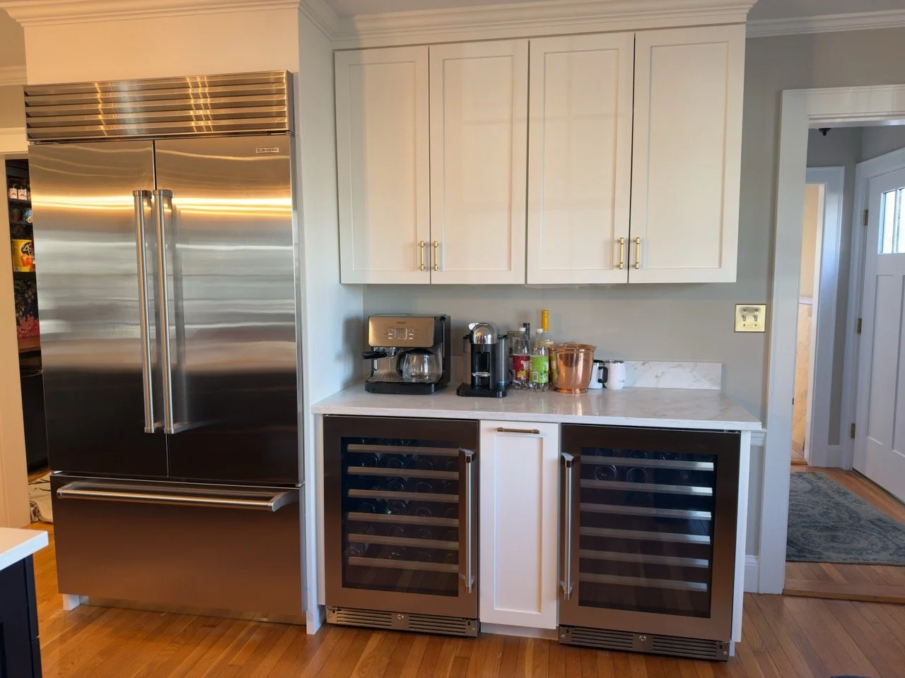 Kitchen with stainless steel refrigerator, cabinetry, countertop, coffee maker, and wine coolers.