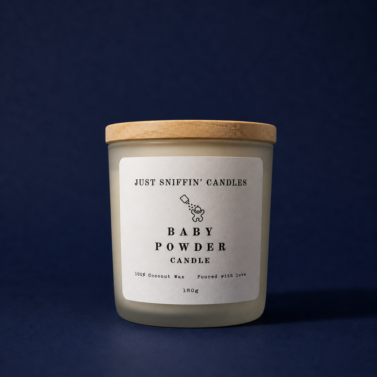 A white candle with a wooden lid, labeled 'Baby Powder Candle' and 'Just Sniffin' Candles', placed against a dark blue background.