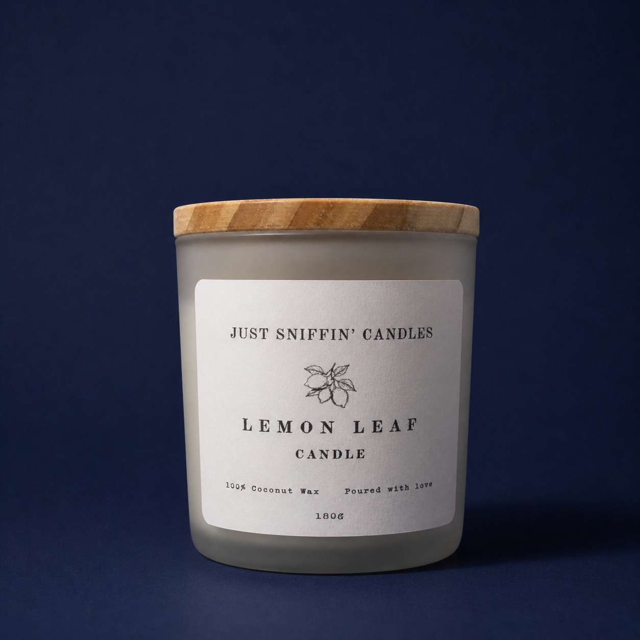 A candle in a frosted glass jar with a wooden lid, labeled "Just Sniffin' Candles Lemon Leaf Candle" with a lemon leaf illustration, on a dark blue background.