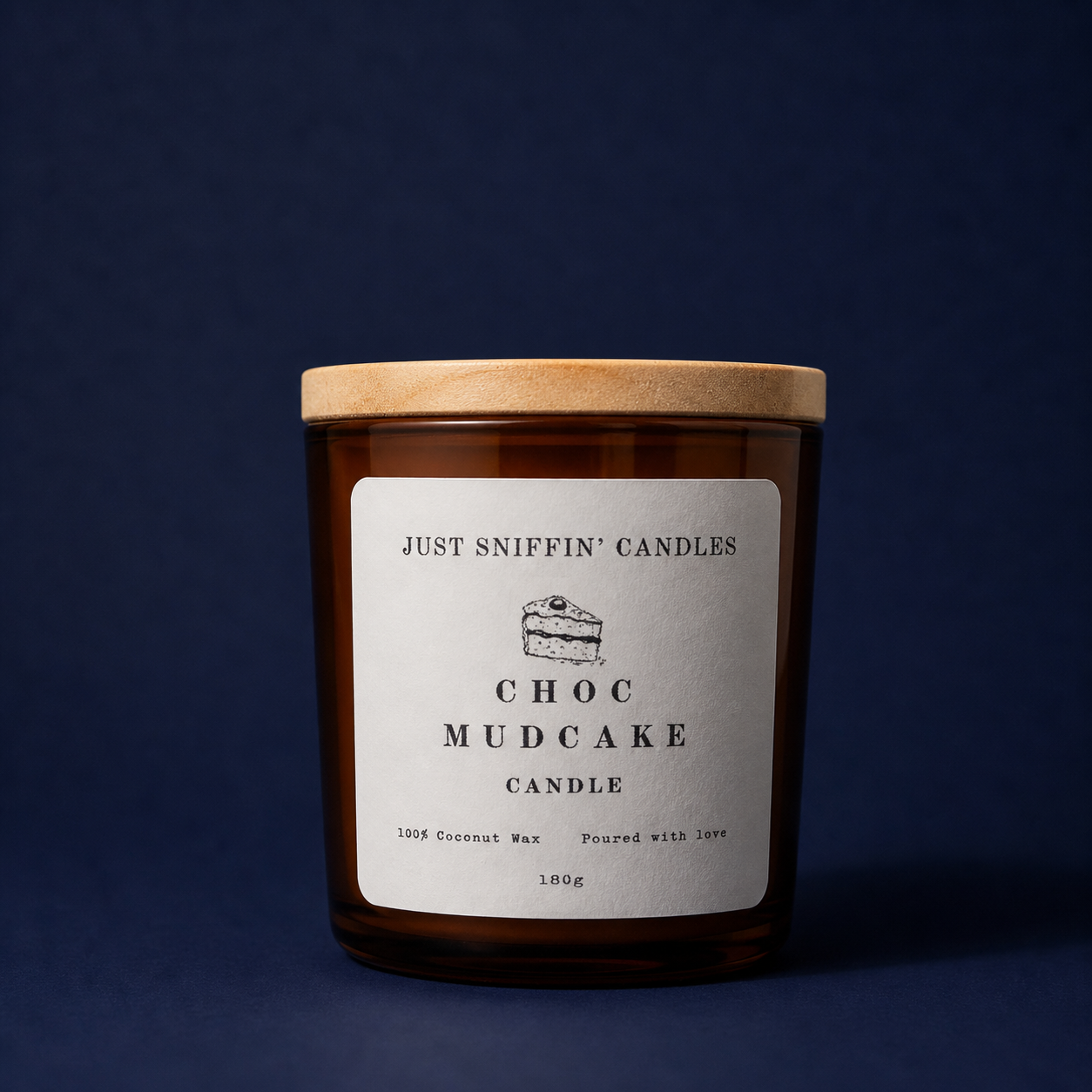 A brown candle jar with a wooden lid labeled 'Just Sniffin' Candles Choc Mudcake Candle' against a dark blue background.
