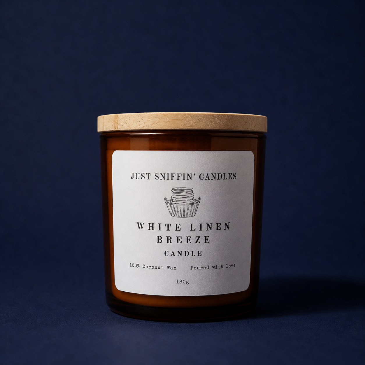 Brown glass candle jar with a wooden lid, labeled 'Just Sniffin' Candles White Linen Breeze Candle,' with a small illustration of a candle in a basket, set against a dark background.