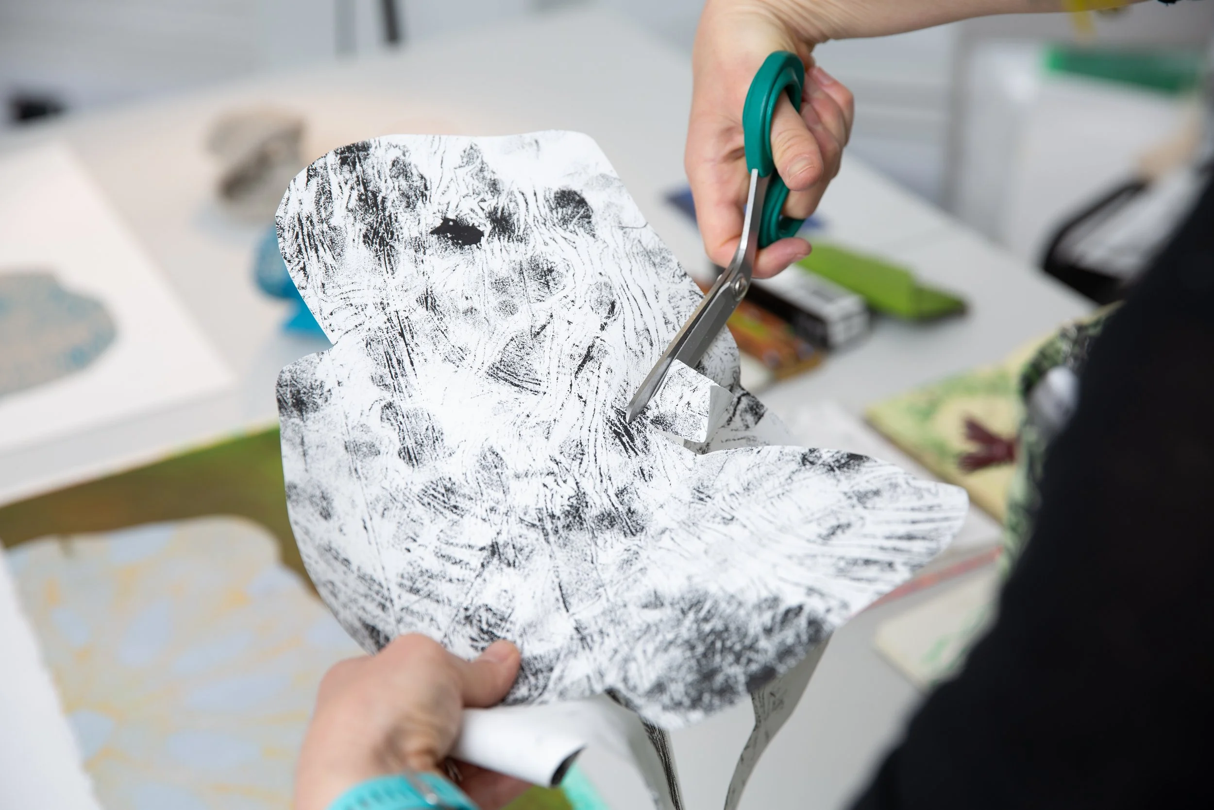 Person using scissors to cut paper with black and white abstract patterns.