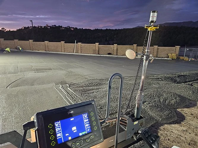 jscreed Construction site at dusk with paving equipment, a digital control panel, and a view of a hill