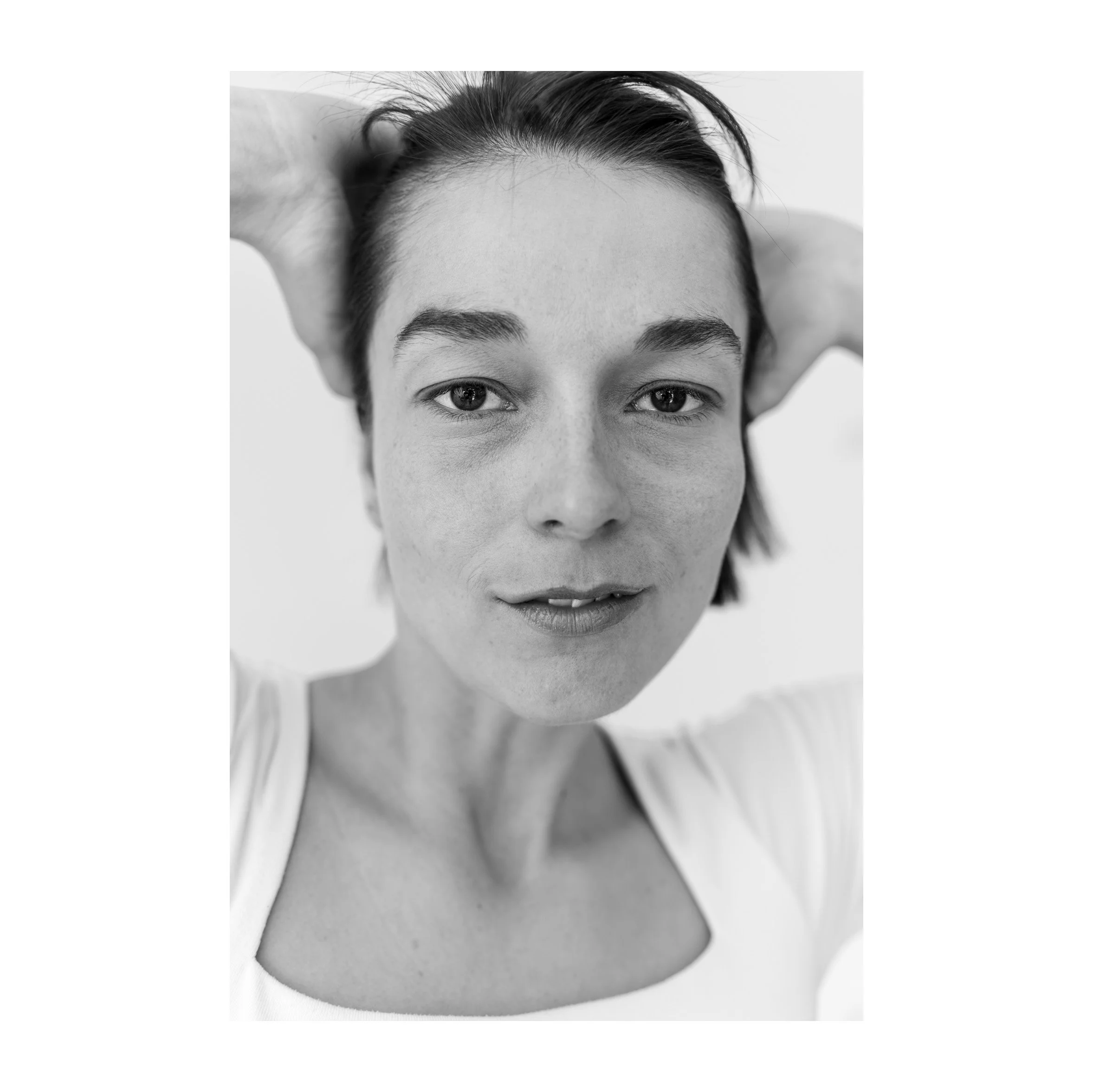 Nahaufnahme einer jungen Frau mit Kurzhaarschnitt, braunen Haaren und braunen Augen, die den Betrachter direkt ansehen, im schwarzen und weißen Foto.
