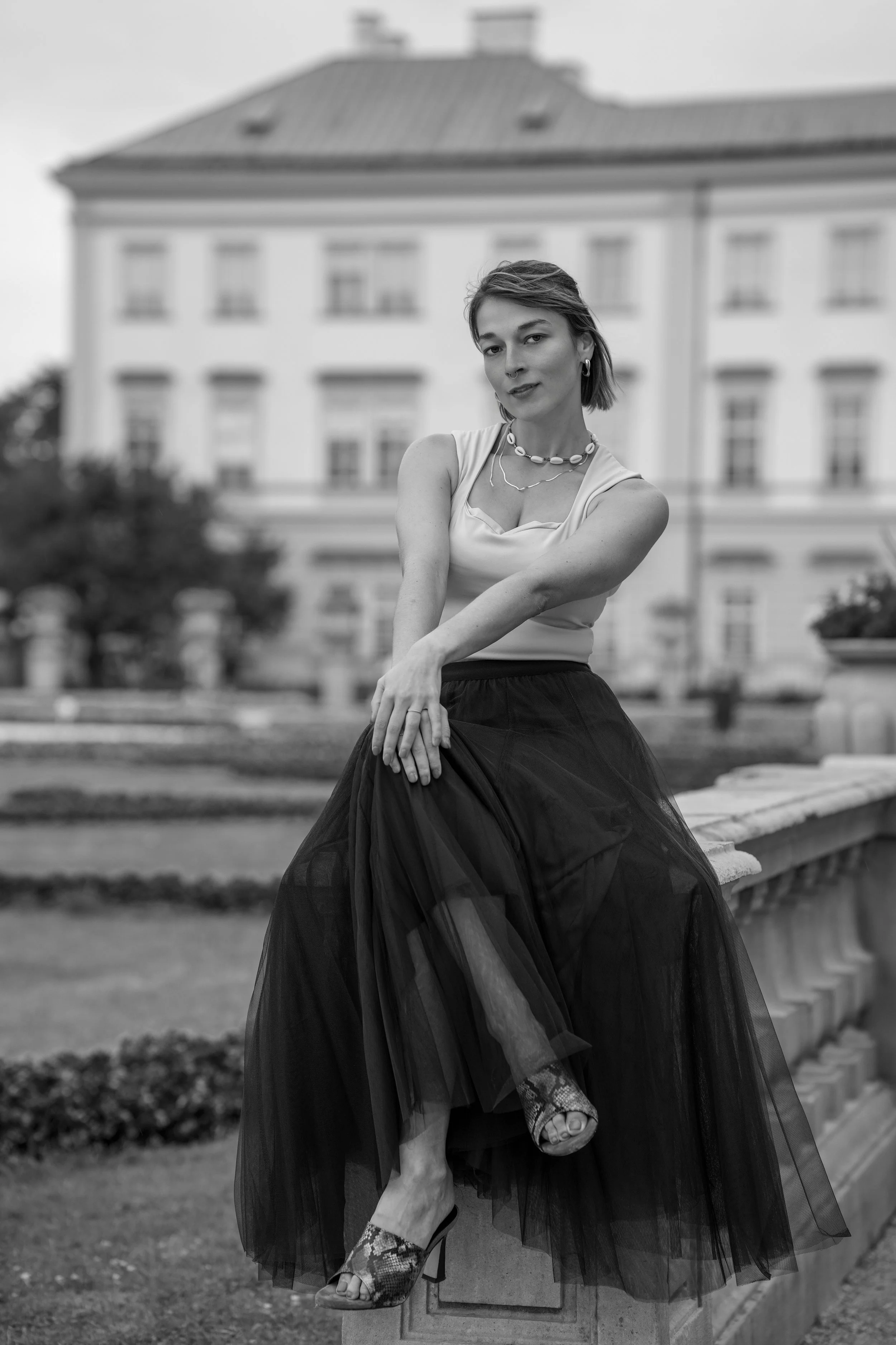 Elegant black-and-white portrait of Sophie in Salzburg’s Mirabell Gardens, framed by historic architecture and soft natural light.
