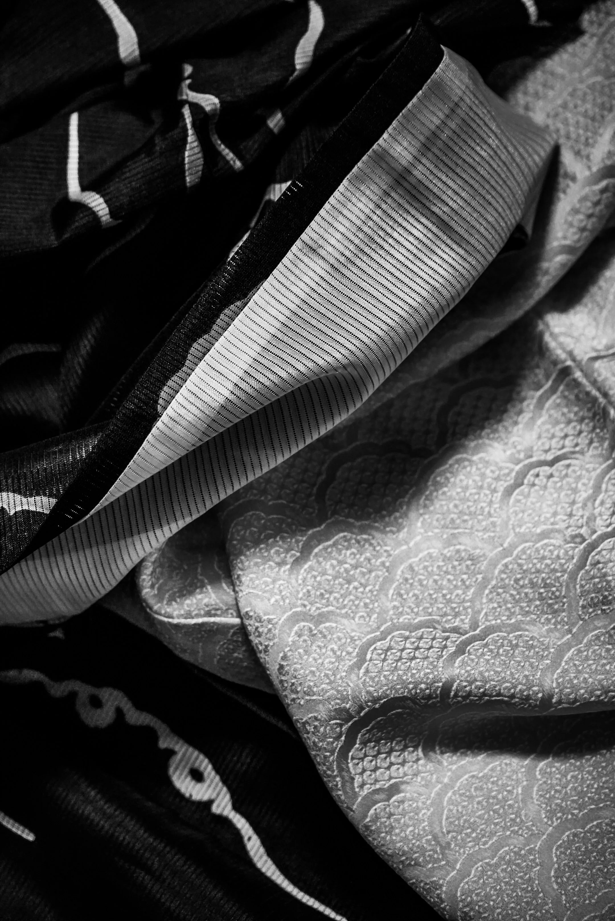 Close-up of decorative patterned fabrics stacked together, with one having a snakeskin pattern and another with fine stripes.