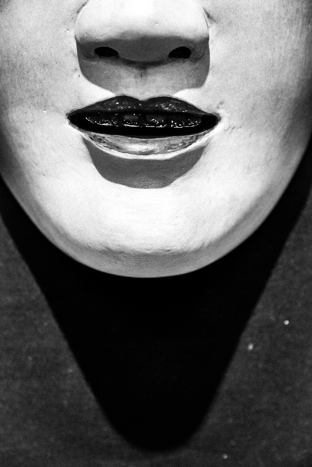 Black and white close-up of a sculpture of a face, focusing on the nose and lips, with the lips slightly parted.