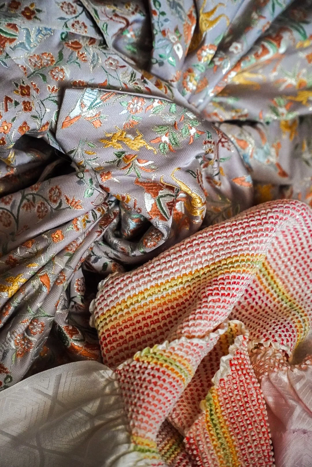 Close-up of colorful, embroidered fabric with floral and dragon designs, featuring a red and white textured cloth with yellow and red accents.