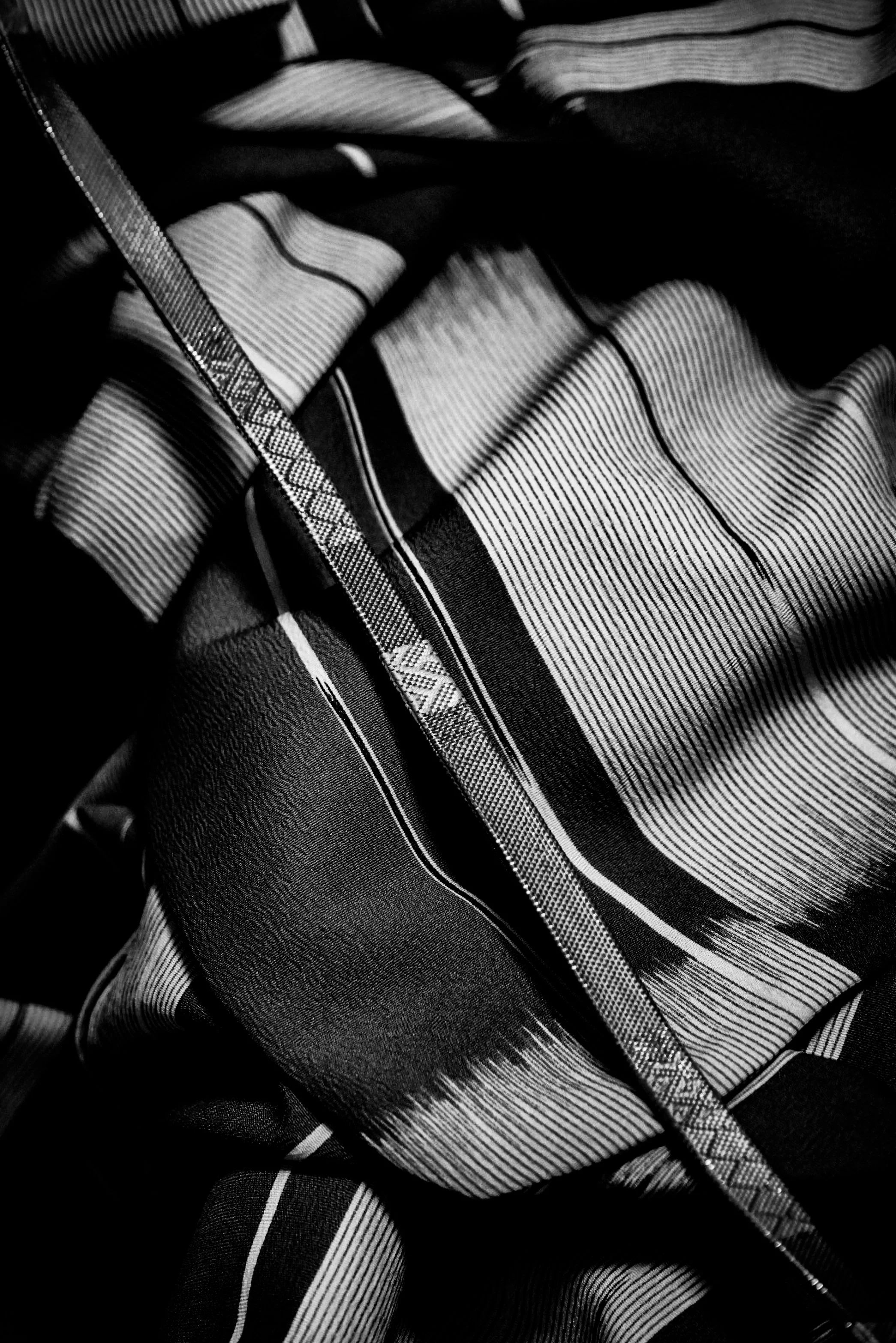 Close-up of a fabric with black and white horizontal and vertical stripes, some overlapping and creating a textured appearance.