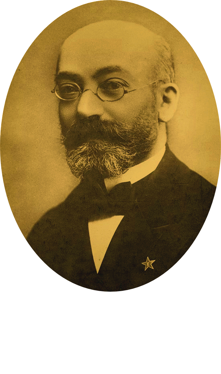 A sepia-toned portrait of Ludwig L. Zamenhof, glasses, dressed in a formal suit with a bow tie, and wearing a star-shaped medal.