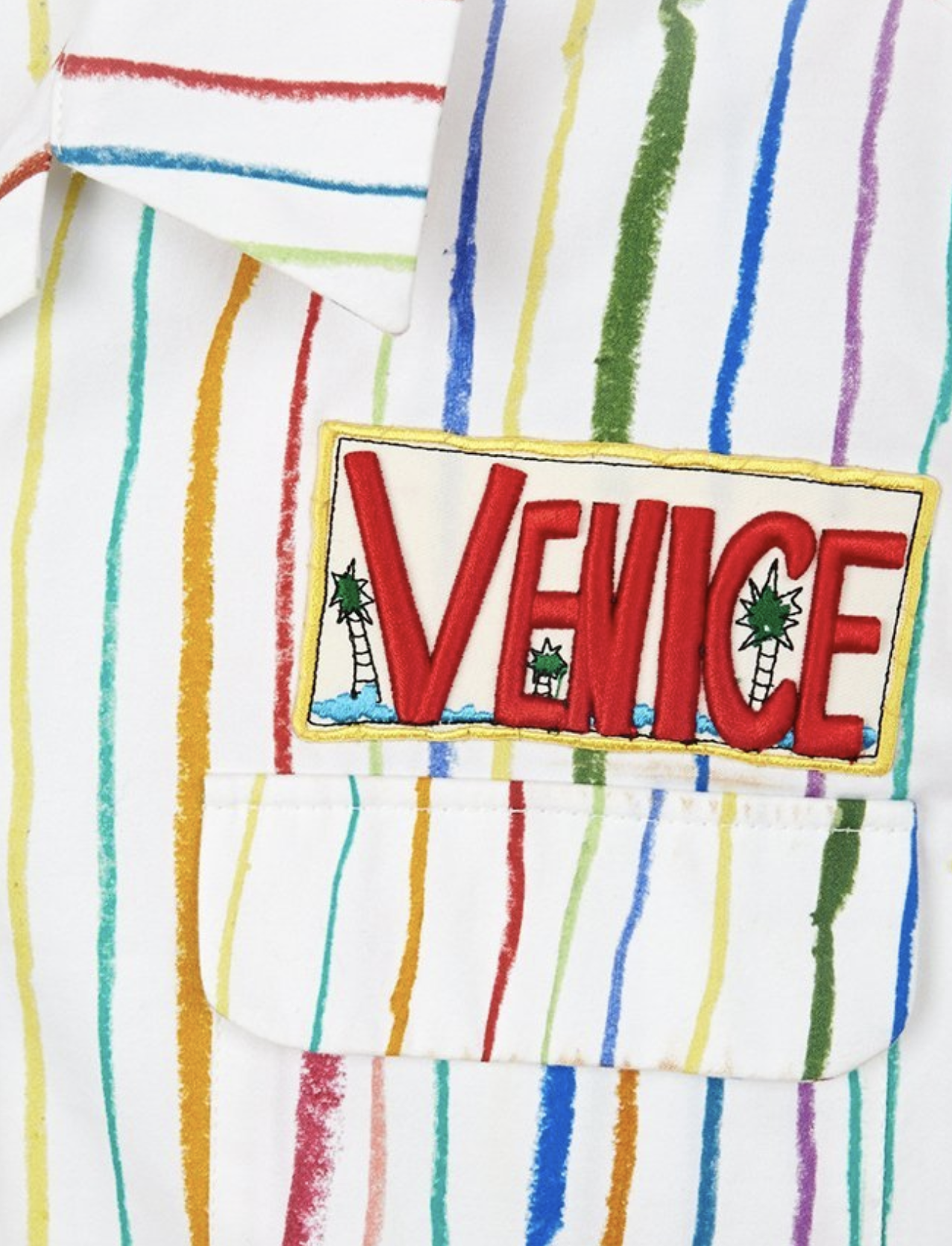 Red Venice appliqué embroidery with palm trees, stitched onto a rainbow-striped shirt pocket