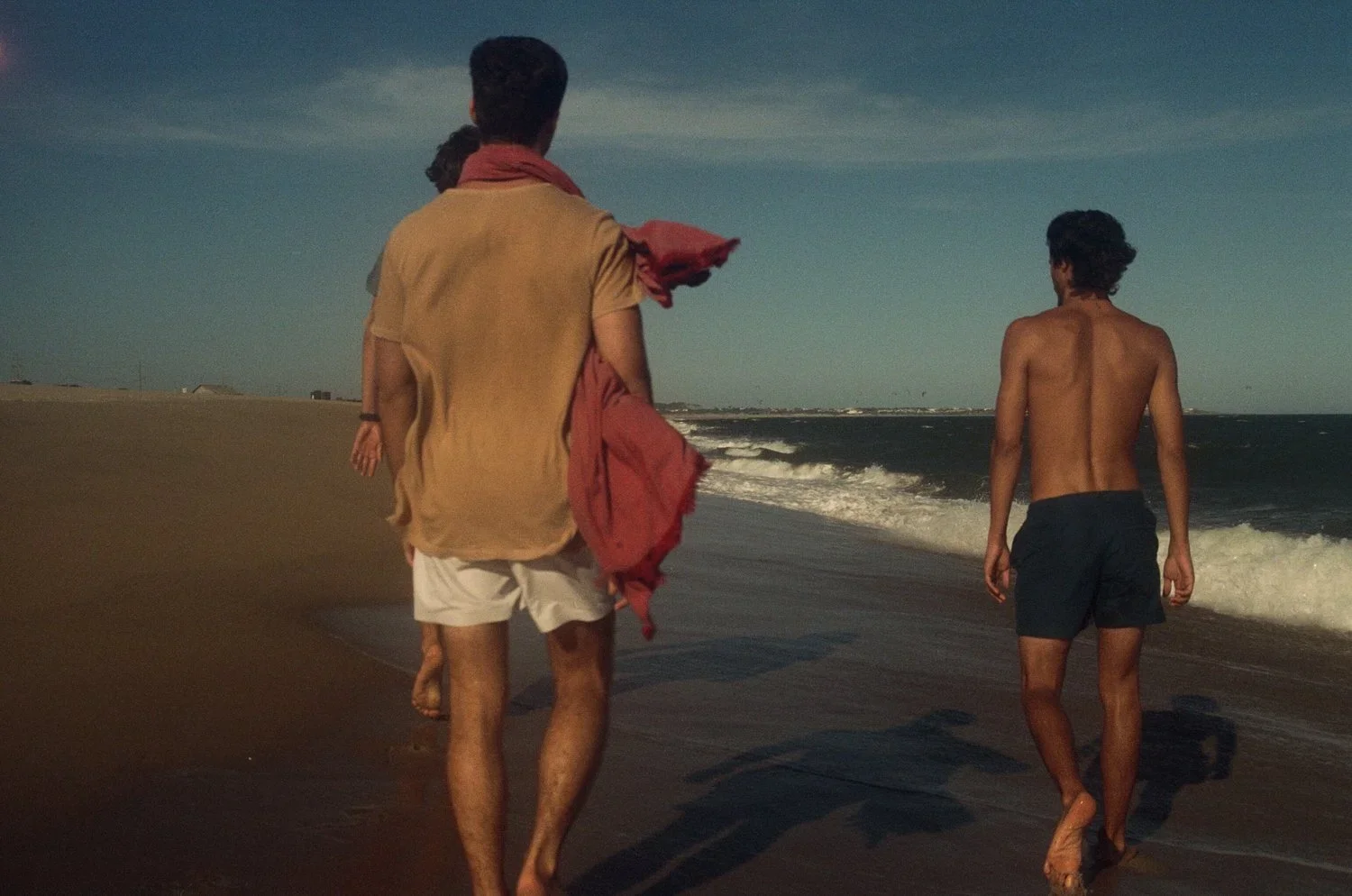 Casa Marane menswear — three men in resort wear walking on the beach at sunset, Punta del Este