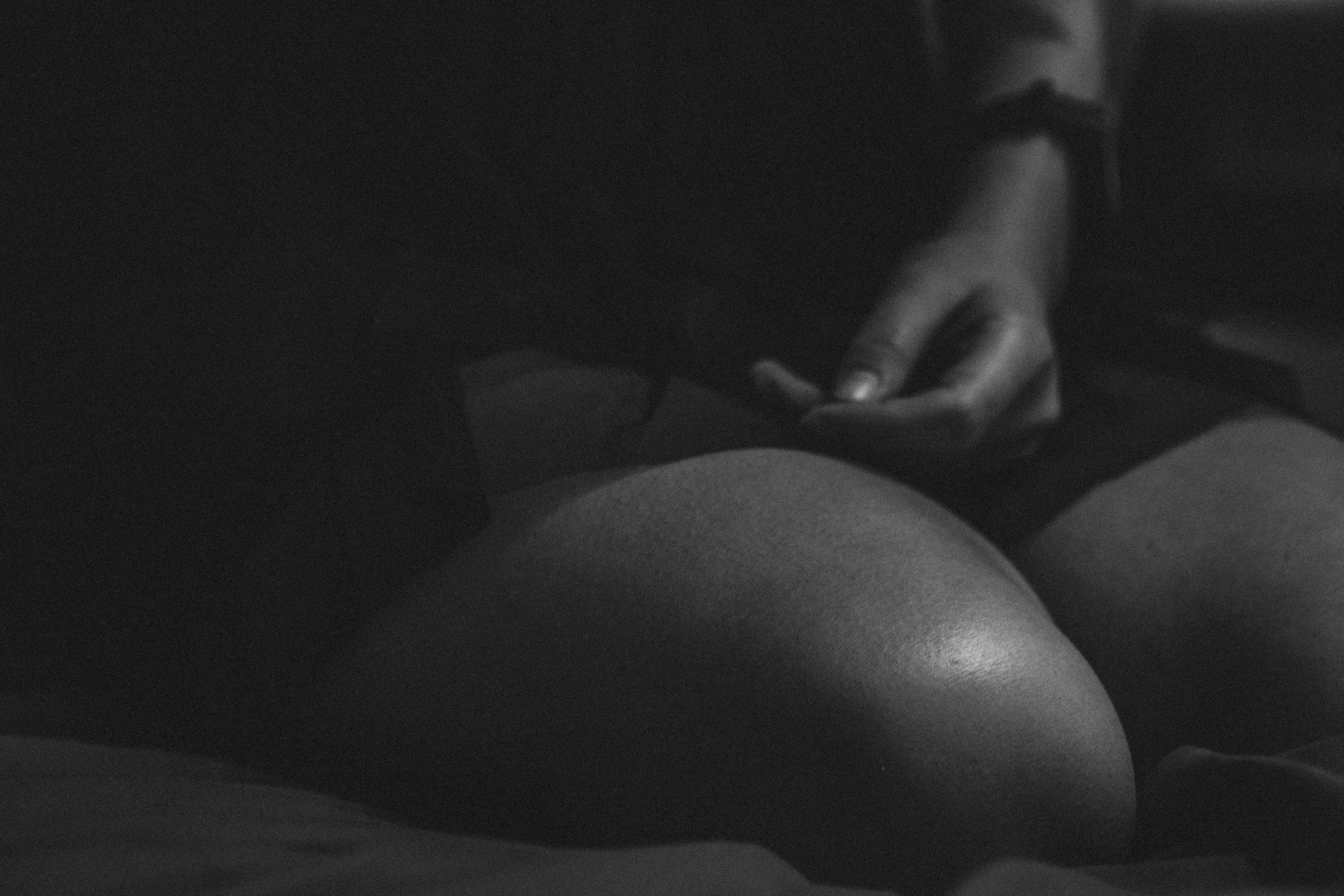 A close-up, black-and-white image showing a hand gently touching a person's knee or thigh area.