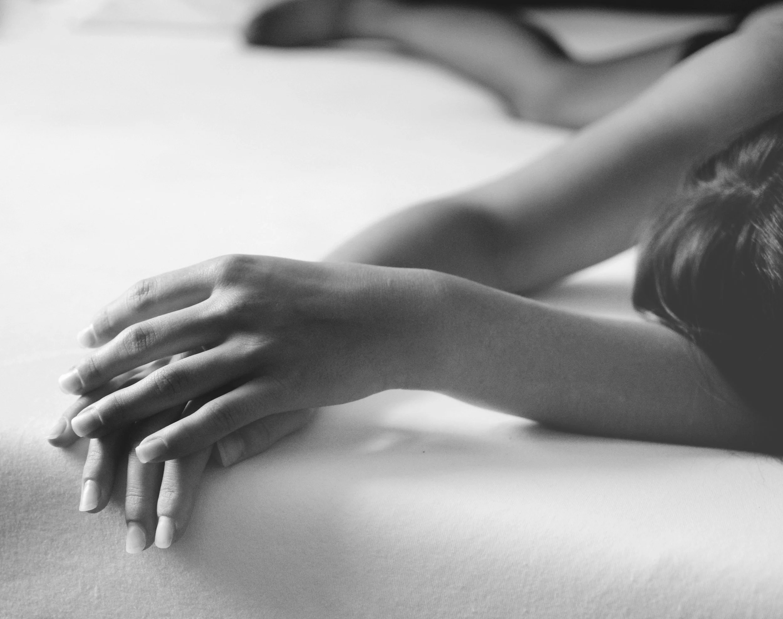Black and white photo of multiple hands placed on top of each other on a flat surface.